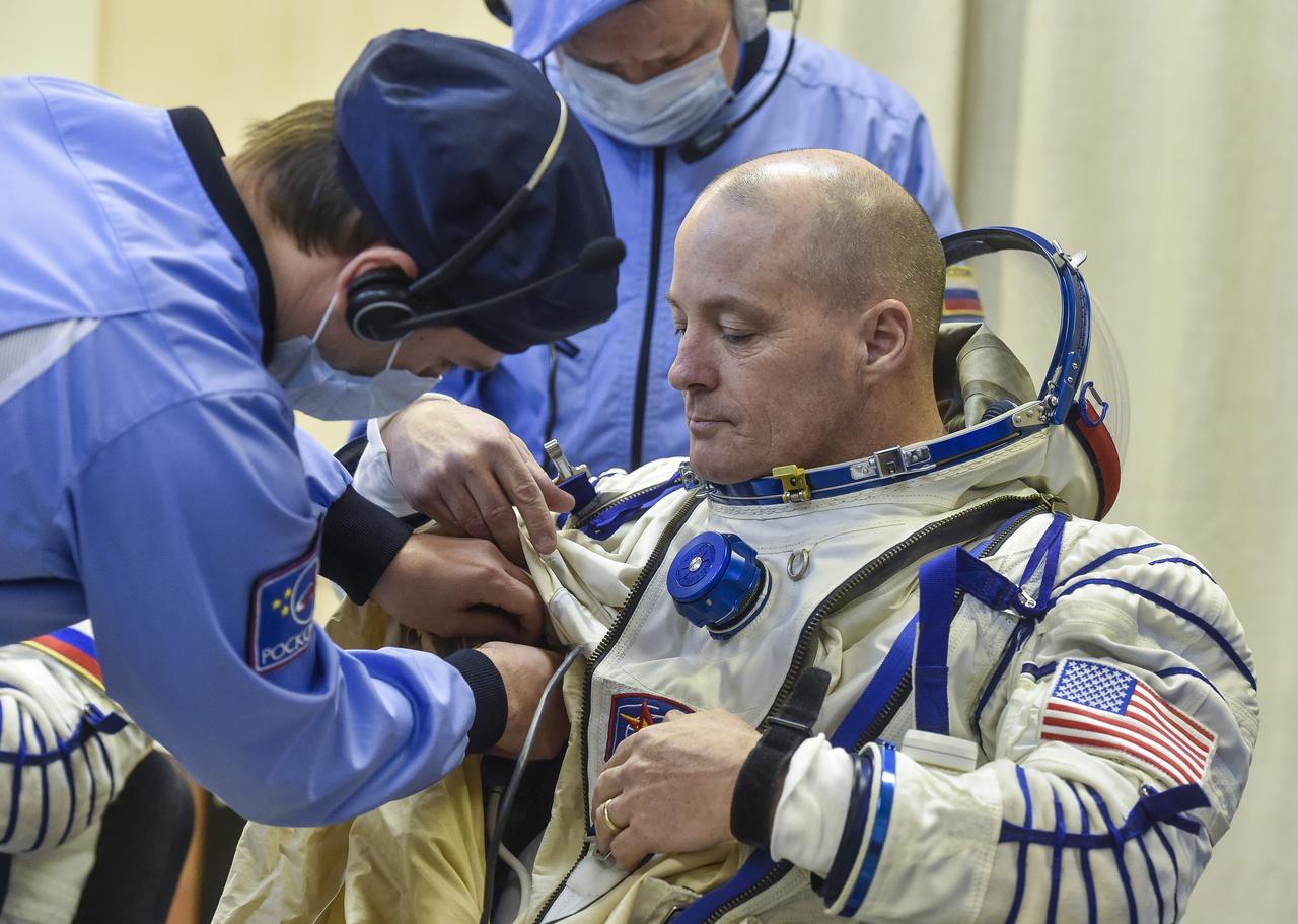Expedition 54 flight engineer Scott Tingle of NASA is helped into his Russian Sokol suit as he and fellow cremates, flight engineer Norishige Kanai of the Japan Aerospace Exploration Agency (JAXA) and Soyuz Commander Anton Shkaplerov of Roscosmos prepare for their Soyuz launch to the International Space Station Sunday, Dec. 17, 2017 in Baikonur, Kazakhstan.  Launch of the Soyuz rocket will send Tingle, Kanai, and Shkaplerov on a five month mission aboard the International Space Station. Photo Credit: (NASA/GCTC/Andrey Shelepin)