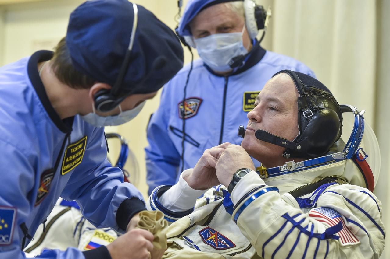 Expedition 54 flight engineer Scott Tingle of NASA is helped into his Russian Sokol suit as he and fellow cremates, flight engineer Norishige Kanai of the Japan Aerospace Exploration Agency (JAXA) and Soyuz Commander Anton Shkaplerov of Roscosmos prepare for their Soyuz launch to the International Space Station Sunday, Dec. 17, 2017 in Baikonur, Kazakhstan.  Launch of the Soyuz rocket will send Tingle, Kanai, and Shkaplerov on a five month mission aboard the International Space Station. Photo Credit: (NASA/GCTC/Andrey Shelepin)