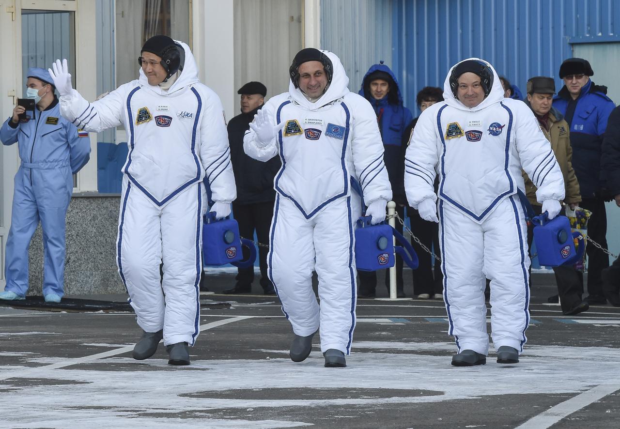 Expedition 54 flight engineer Norishige Kanai of Japan Aerospace Exploration Agency (JAXA), left, Soyuz Commander Anton Shkaplerov of Roscosmos, center, and flight engineer Scott Tingle of NASA are seen as they depart Building 254 and report to mission managers ahead of their launch to the International Space Station Sunday, Dec. 17, 2017 at the Baikonur Cosmodrome Kazakhstan. Launch of the Soyuz rocket will send Kanai, Shkaplerov, and Tingle on a five month mission aboard the International Space Station. Photo Credit: (NASA/GCTC/Andrey Shelepin)