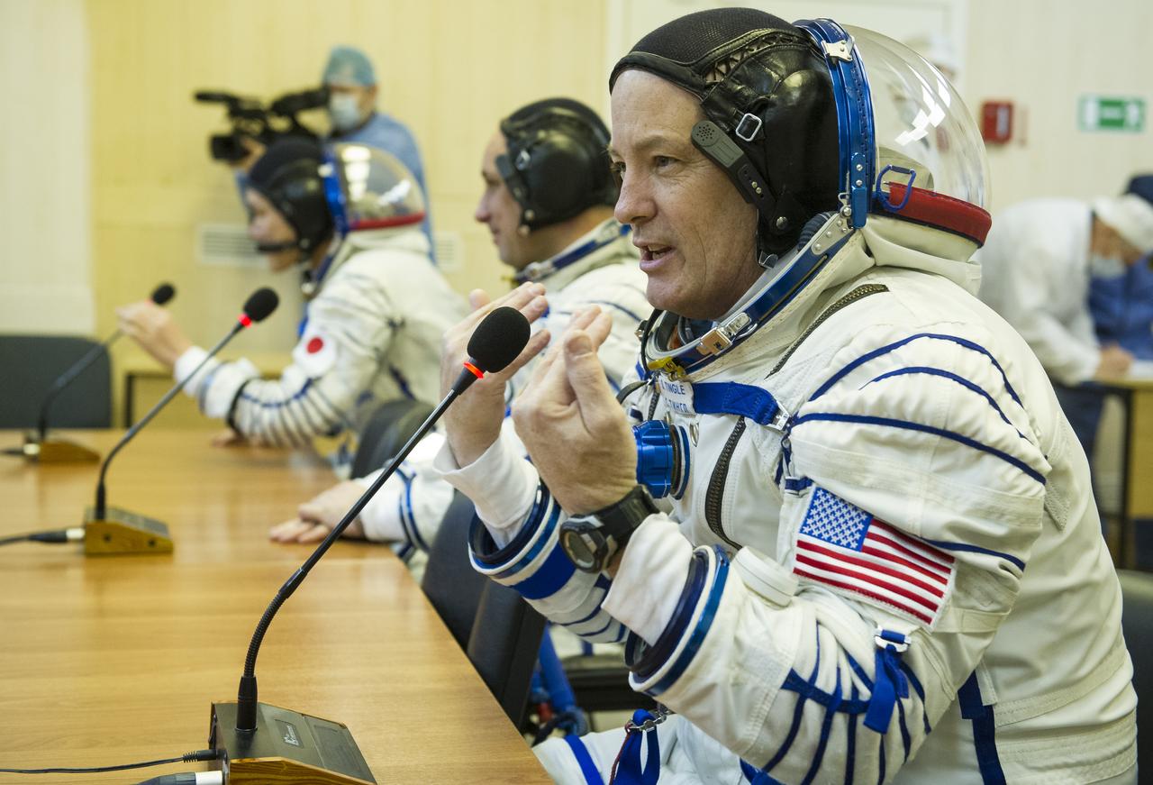 Expedition 54 flight engineer Scott Tingle of NASA speaks to family and friends along with Soyuz Commander Anton Shkaplerov of Roscosmos, and flight engineer Norishige Kanai of Japan Aerospace Exploration Agency (JAXA) after having their Russian Sokol suits pressure checked ahead of their Soyuz launch to the International Space Station Sunday, Dec. 17, 2017 in Baikonur, Kazakhstan.  Launch of the Soyuz rocket will send Tingle, Kanai, and Shkaplerov on a five month mission aboard the International Space Station. Photo Credit: (NASA/GCTC/Andrey Shelepin)