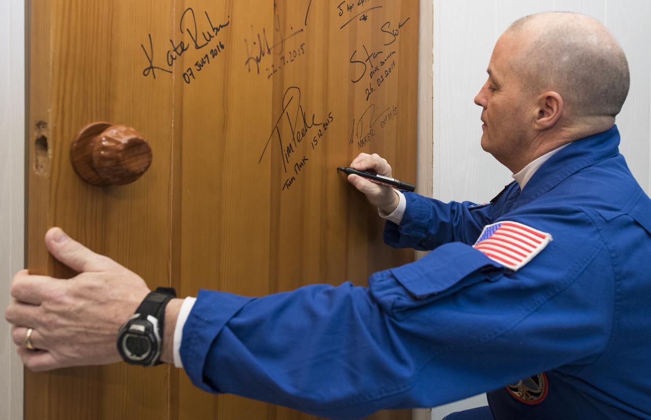 Expedition 54 flight engineer Scott Tingle of NASA performs the traditional door signing at the Cosmonaut Hotel prior to departing the hotel for launch on a Soyuz rocket with fellow cremates flight engineer Norishige Kanai of Japan Aerospace Exploration Agency (JAXA) and Soyuz Commander Anton Shkaplerov of Roscosmos, Sunday, Dec. 17, 2017 in Baikonur, Kazakhstan. Tingle, Shkaplerov, and Kanai will launch in their Soyuz MS-07 to the International Space Station to begin a five month mission. Photo Credit: (NASA/Joel Kowsky)