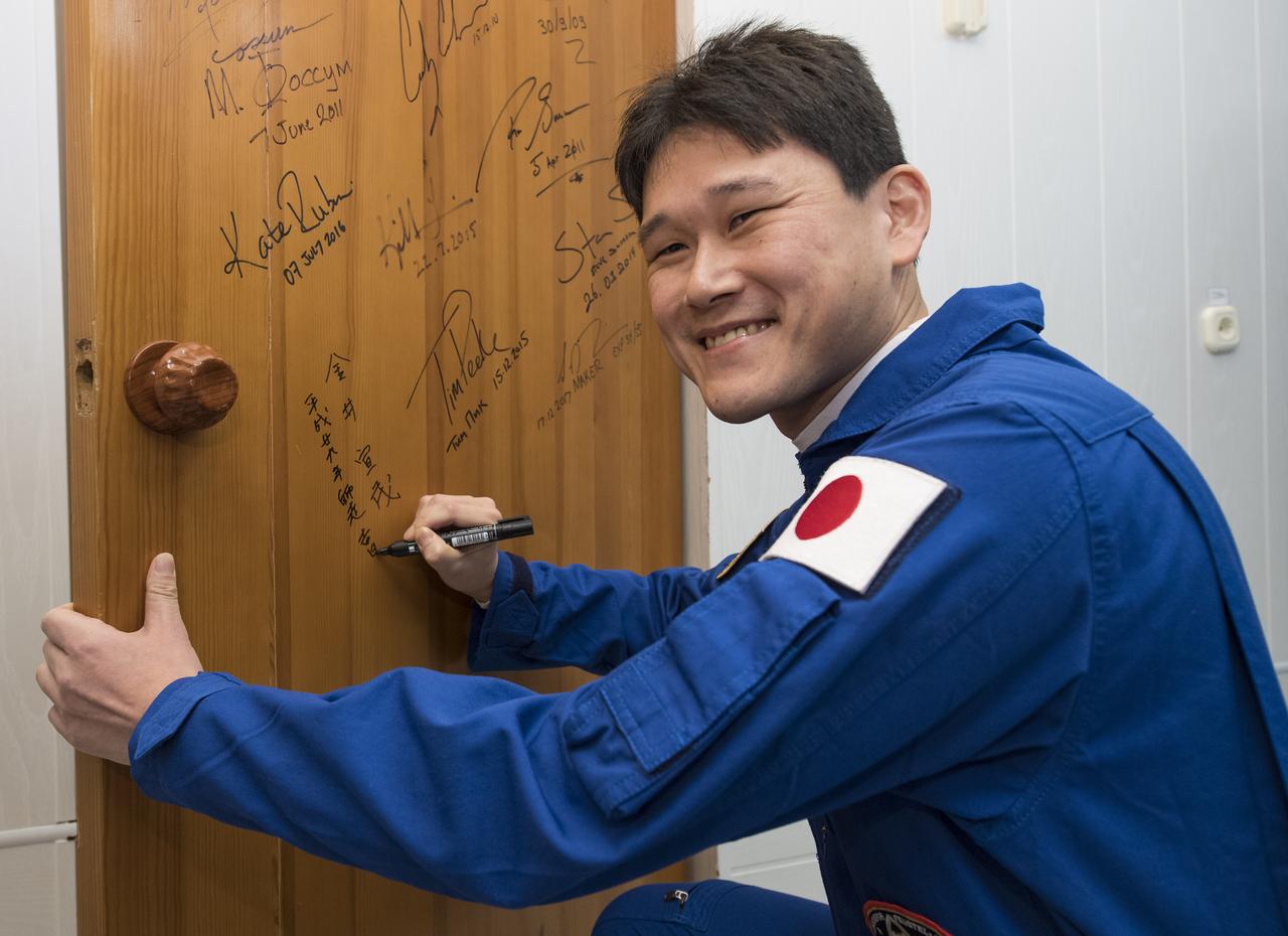 Expedition 54 flight engineer Norishige Kanai of the Japan Aerospace Exploration Agency (JAXA) performs the traditional door signing at the Cosmonaut Hotel prior to departing the hotel for launch on a Soyuz rocket with fellow cremates flight engineer Norishige Kanai of Japan Aerospace Exploration Agency (JAXA) and flight engineer Scott Tingle of NASA, Sunday, Dec. 17, 2017 in Baikonur, Kazakhstan. Kanai, Shkaplerov, and Tingle will launch in their Soyuz MS-07 to the International Space Station to begin a five month mission. Photo Credit: (NASA/Joel Kowsky)