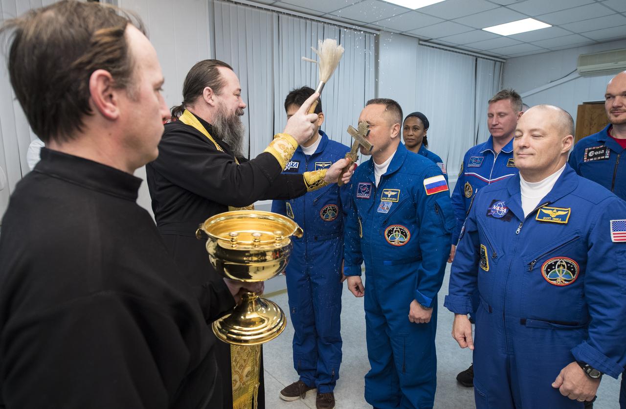 Expedition 54 Soyuz Commander Anton Shkaplerov of Roscosmos receives the traditional blessing from a Russian Orthodox Priest at the Cosmonaut Hotel prior to his launch aboard the Soyuz MS-07 spacecraft to the International Space Station, Sunday, Dec. 17, 2017 in Baikonur, Kazakhstan.  Shkaplerov, flight engineer Scott Tingle of NASA, and flight engineer Norishige Kanai of the Japan Aerospace Exploration Agency (JAXA) will spend the next five months living and working onboard the International Space Station.  Photo Credit: (NASA/Joel Kowsky)