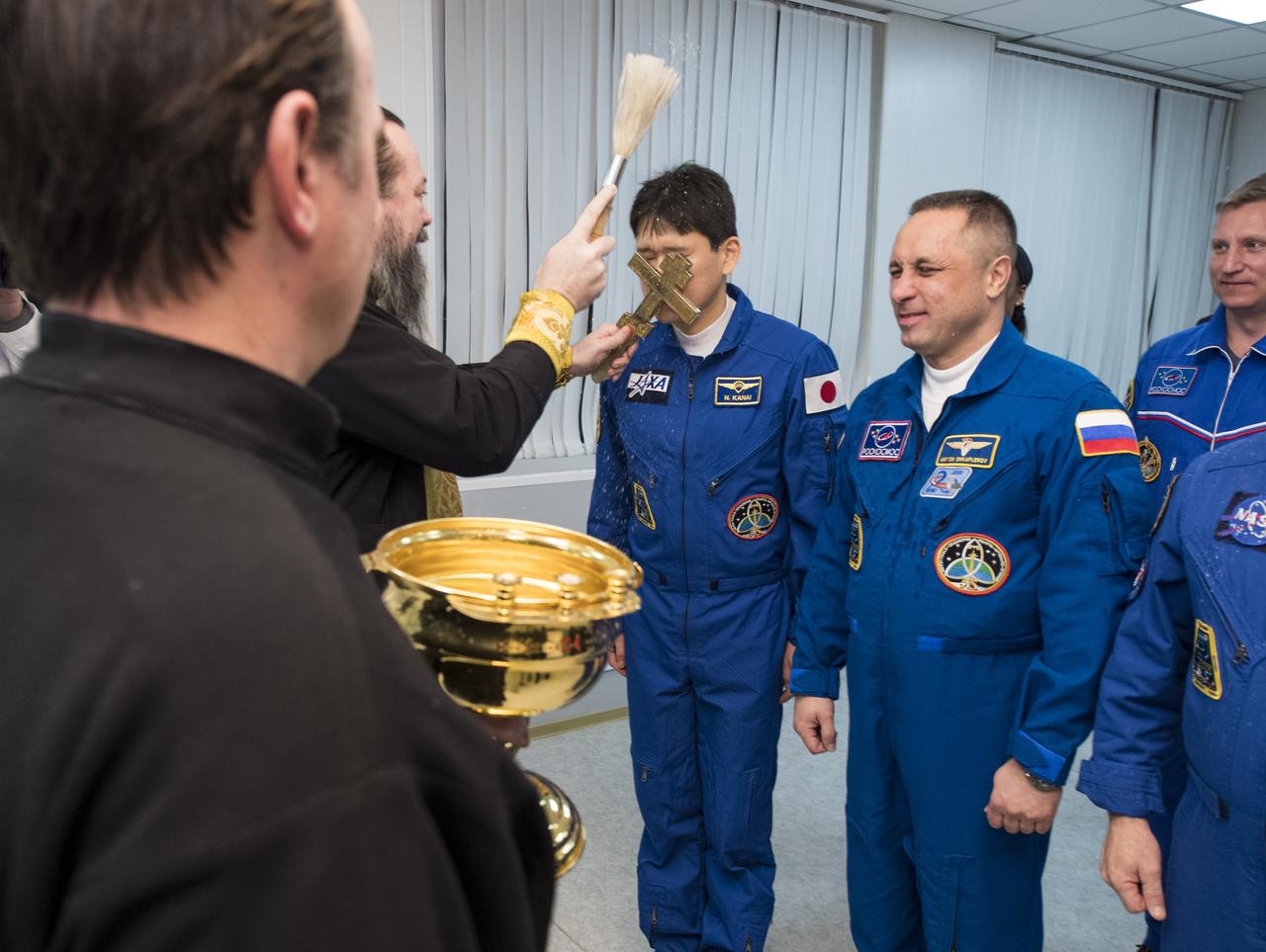 Expedition 54 flight engineer Norishige Kanai of the Japan Aerospace Exploration Agency (JAXA) receives the traditional blessing from a Russian Orthodox Priest at the Cosmonaut Hotel prior to his launch aboard the Soyuz MS-07 spacecraft to the International Space Station, Sunday, Dec. 17, 2017 in Baikonur, Kazakhstan.  Kanai, flight engineer Scott Tingle of NASA, and Soyuz Commander Anton Shkaplerov of Roscosmos will spend the next five months living and working onboard the International Space Station.  Photo Credit: (NASA/Joel Kowsky)