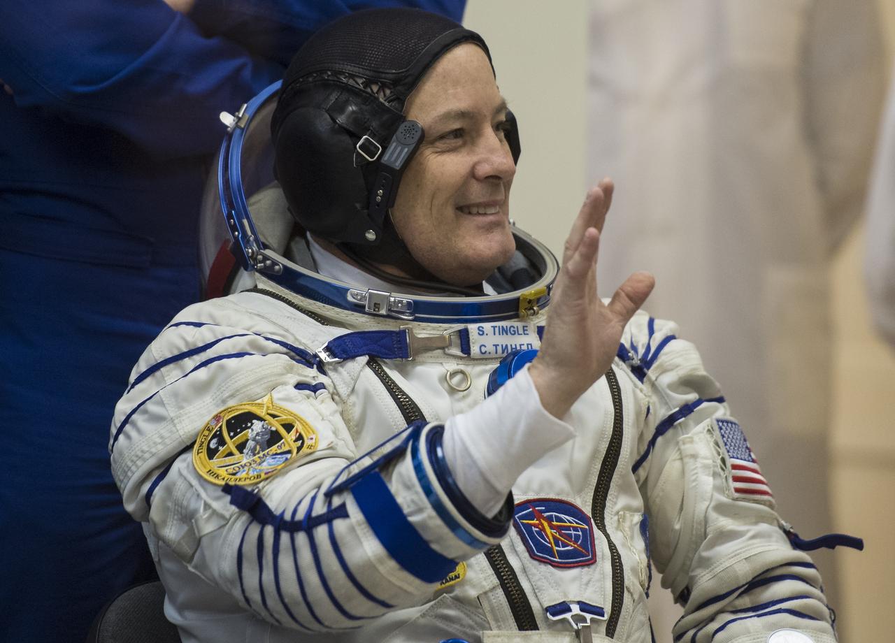 Expedition 54 flight engineer Scott Tingle of NASA waves as he waits to have his Russian Sokol suit pressure checked in preparation for launch aboard the Soyuz MS-07 spacecraft, Sunday, Dec. 17, 2017 at the Baikonur Cosmodrome Kazakhstan. Launch of the Soyuz rocket will send Tingle and fellow crewmates Soyuz Commander Anton Shkaplerov of Roscosmos and flight engineer Norishige Kanai of the Japan Aerospace Exploration Agency (JAXA) on a five month mission aboard the International Space Station. Photo Credit: (NASA/Joel Kowsky)