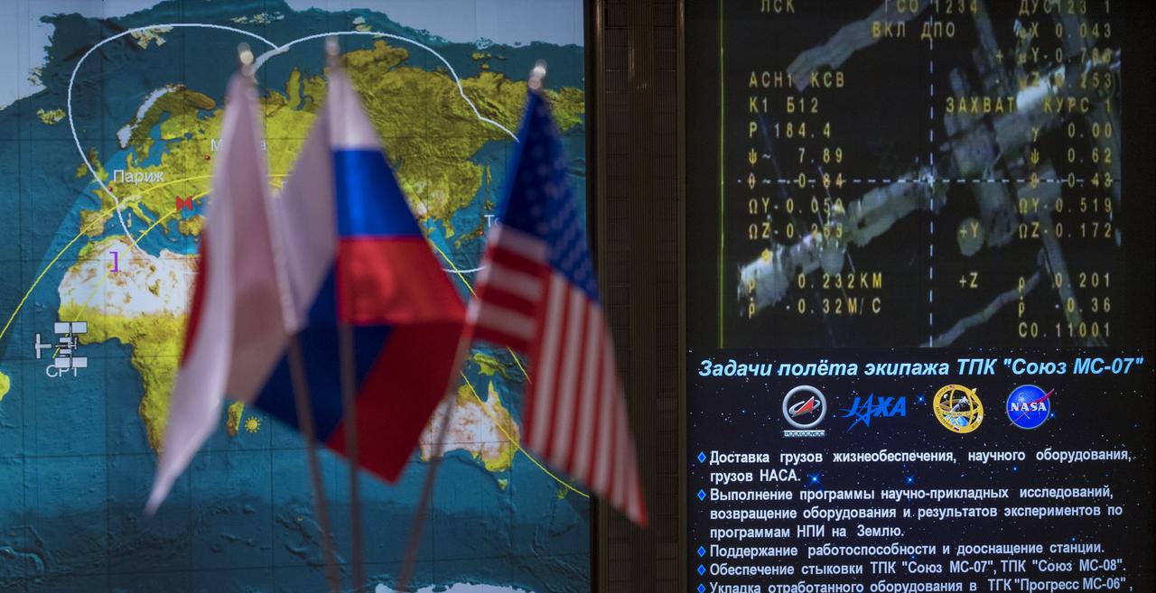 Icons for the International Space Station and Soyuz MS-07 spacecraft are seen on a tracking map along with live video of the International Space Station are seen on screen in the Moscow Mission Control Center as the Soyuz MS-07 spacecraft approaches for docking, Tuesday, Dec. 19, 2017 in Korolev, Russia. The Soyuz MS-07 spacecraft carrying Anton Shkaplerov of Roscosmos, Scott Tingle of NASA, and Norishige Kanai of the Japan Aerospace Exploration Agency (JAXA) docked with the International Space Station at 3:39 a.m. EST, Tuesday, Dec. 19 while 250 statute miles over the southern coast of Italy and joined Expedition 54 Commander  Alexander Misurkin of Roscosmos, and NASA astronauts Joe Acaba and Mark Vande Hei. Photo Credit: (NASA/Joel Kowsky)