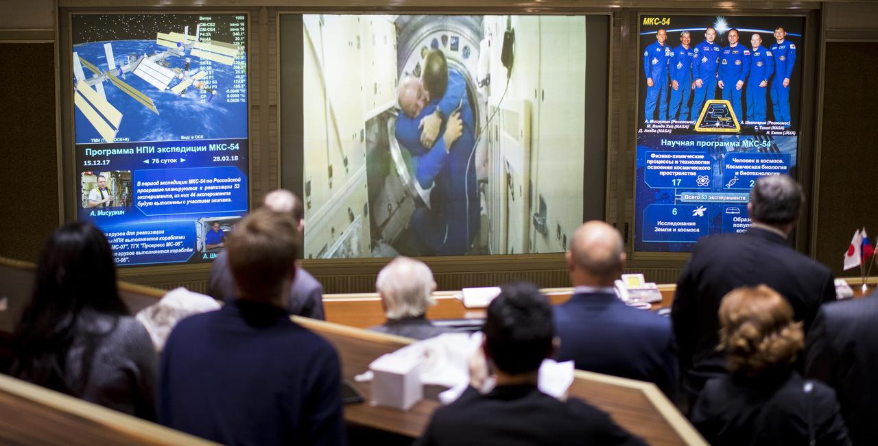 Scott Tingle of NASA is seen embracing Expedition 54 Commander Alexander Misurkin after the opening of the hatches between the Soyuz MS-07 spacecraft and the International Space Station on the screens in the Moscow Mission Control Center in Korolev, Russia a few hours after the Soyuz MS-07 docked to the International Space Station on Tuesday, Dec. 19, 2017. Hatches were opened at 5:55 a.m. EST and Tingle, Anton Shkaplerov of Roscosmos, and Norishige Kanai of the Japan Aerospace Exploration Agency (JAXA) joined Expedition 54 Commander Alexander Misurkin of Roscosmos and crewmates Mark Vande Hei and Joe Acaba of NASA aboard the orbiting laboratory. Photo Credit: (NASA/Joel Kowsky)