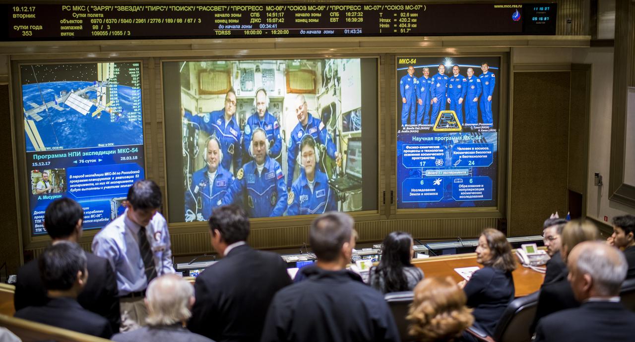 Expedition 54 flight engineers Scott Tingle of NASA, bottom left, Anton Shkaplerov of Roscosmos, bottom center, and Norishige Kanai of the Japan Aerospace Exploration Agency (JAXA) bottom right, are seen with flight engineer Joe Acaba of NASA, top left, Commander Alexander Misurkin, top center, and flight engineer Mark Vande Hei of NASA, top right, on a video monitor as they U.S. Ambassador to Russia Jon Huntsman Jr. at the Moscow Mission Control Center in Korolev, Russia a few hours after the Soyuz MS-07 docked to the International Space Station on Tuesday, Dec. 19, 2017. Photo Credit: (NASA/Joel Kowsky)