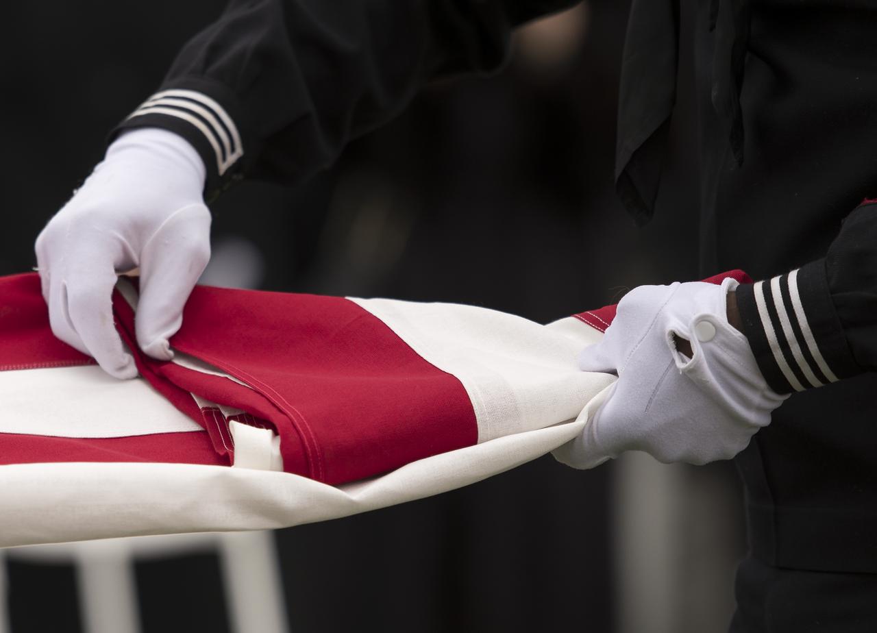 The flag that draped the casket of former NASA astronaut Captain Bruce McCandless II, USN (Ret.) is folded during his interment service, Tuesday, Jan. 16, 2018 at the United States Naval Academy Cemetery in Annapolis, Maryland. Photo Credit: (NASA/Bill Ingalls)