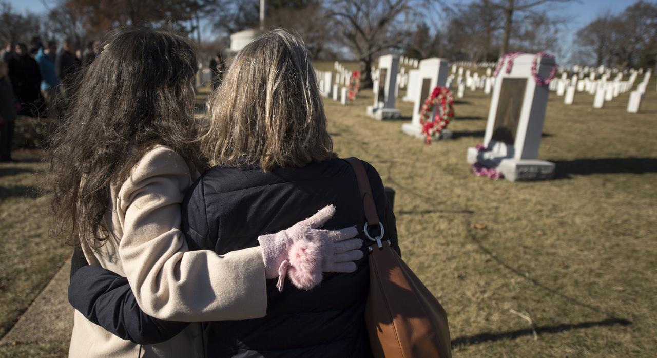 Amy Resnik, sister-in-law of the late space shuttle Challenger astronaut Judy Resnik, left, and Kristy Carroll, family friend of the late space shuttle Columbia astronaut William McCool embrace by the Space Shuttle Columbia and Challenger Memorials during NASA's Day of Remembrance, Thursday, Jan. 25, 2018, at Arlington National Cemetery in Arlington, Virginia. Wreaths were laid in memory of those men and women who lost their lives in the quest for space exploration. Photo Credit: (NASA/Bill Ingalls)