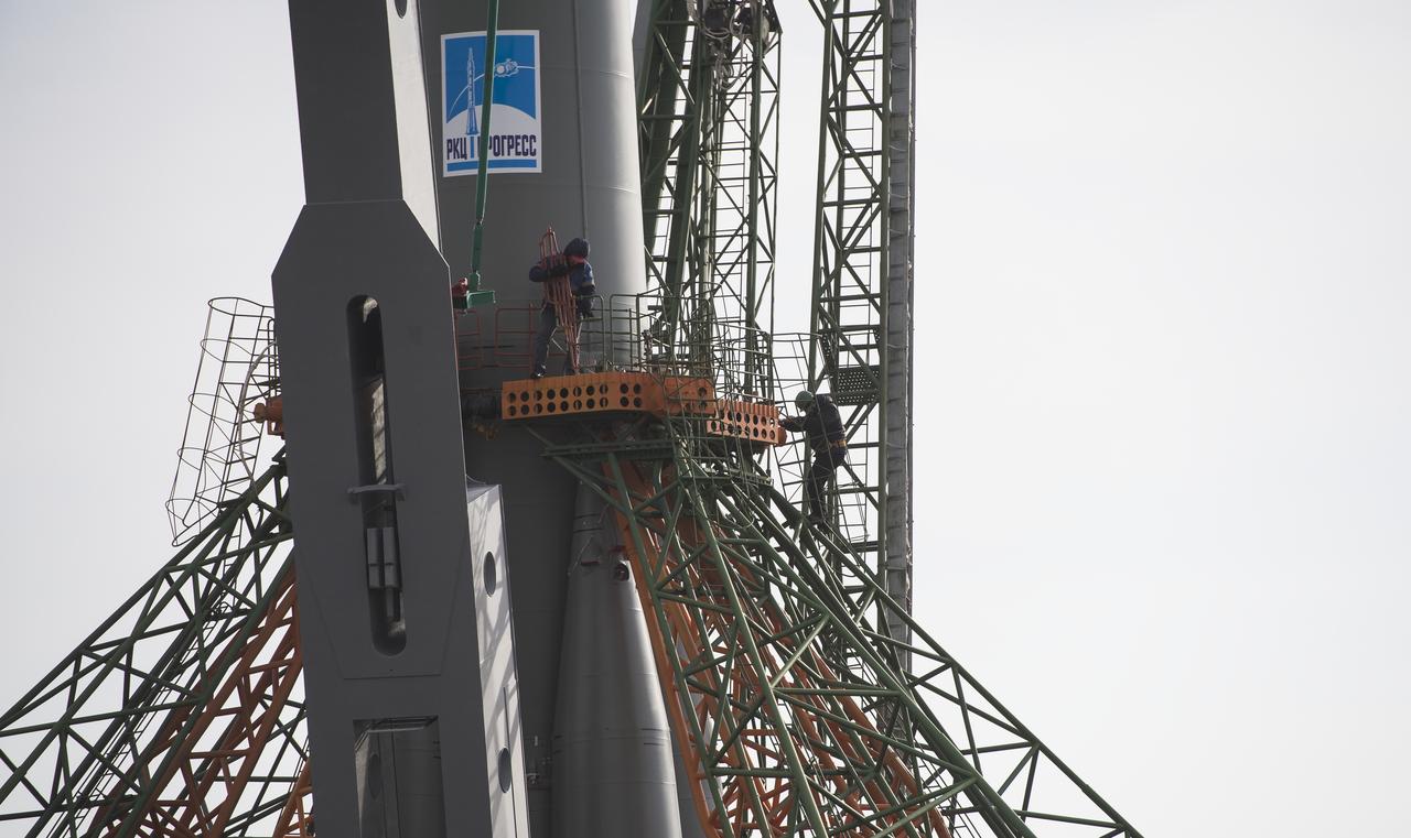 Workers are seen on a gantry after the Soyuz rocket was raised into a vertical position on the launch pad, Monday, March 19, 2018 at the Baikonur Cosmodrome in Kazakhstan. Expedition 55 crewmembers Ricky Arnold and Drew Feustel of NASA and Oleg Artemyev of Roscosmos are scheduled to launch at 1:44 p.m. Eastern time (11:44 p.m. Baikonur time) on March 21 and will spend the next five months living and working aboard the International Space Station. Photo Credit: (NASA/Joel Kowsky)