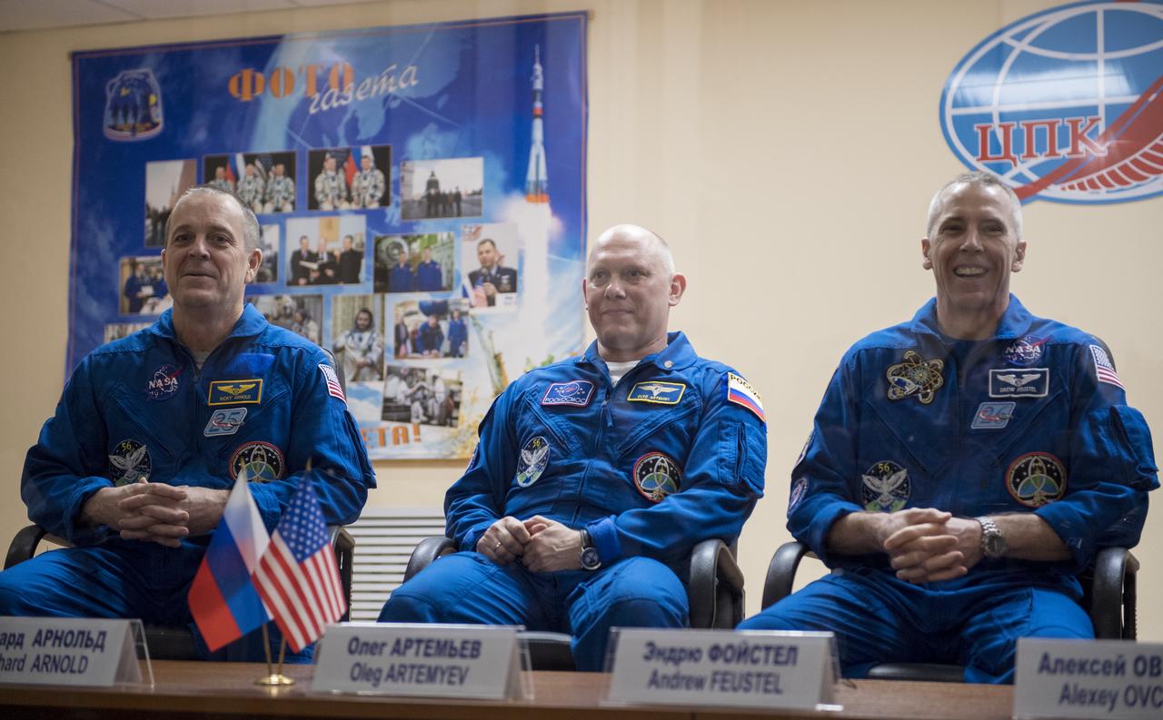 Expedition 55 flight engineer Ricky Arnold of NASA, left, Soyuz Commander Oleg Artemyev of Roscosmos, center, and flight engineer Drew Feustel of NASA, right, are seen in quarantine, behind glass, during a press conference, Tuesday, March 20, 2018 a the Cosmonaut Hotel in Baikonur, Kazakhstan. Arnold, Artemyev, and Feustel are scheduled to launch to the International Space Station aboard the Soyuz MS-08 spacecraft on Wednesday, March, 21.  Photo Credit: (NASA/Joel Kowsky)