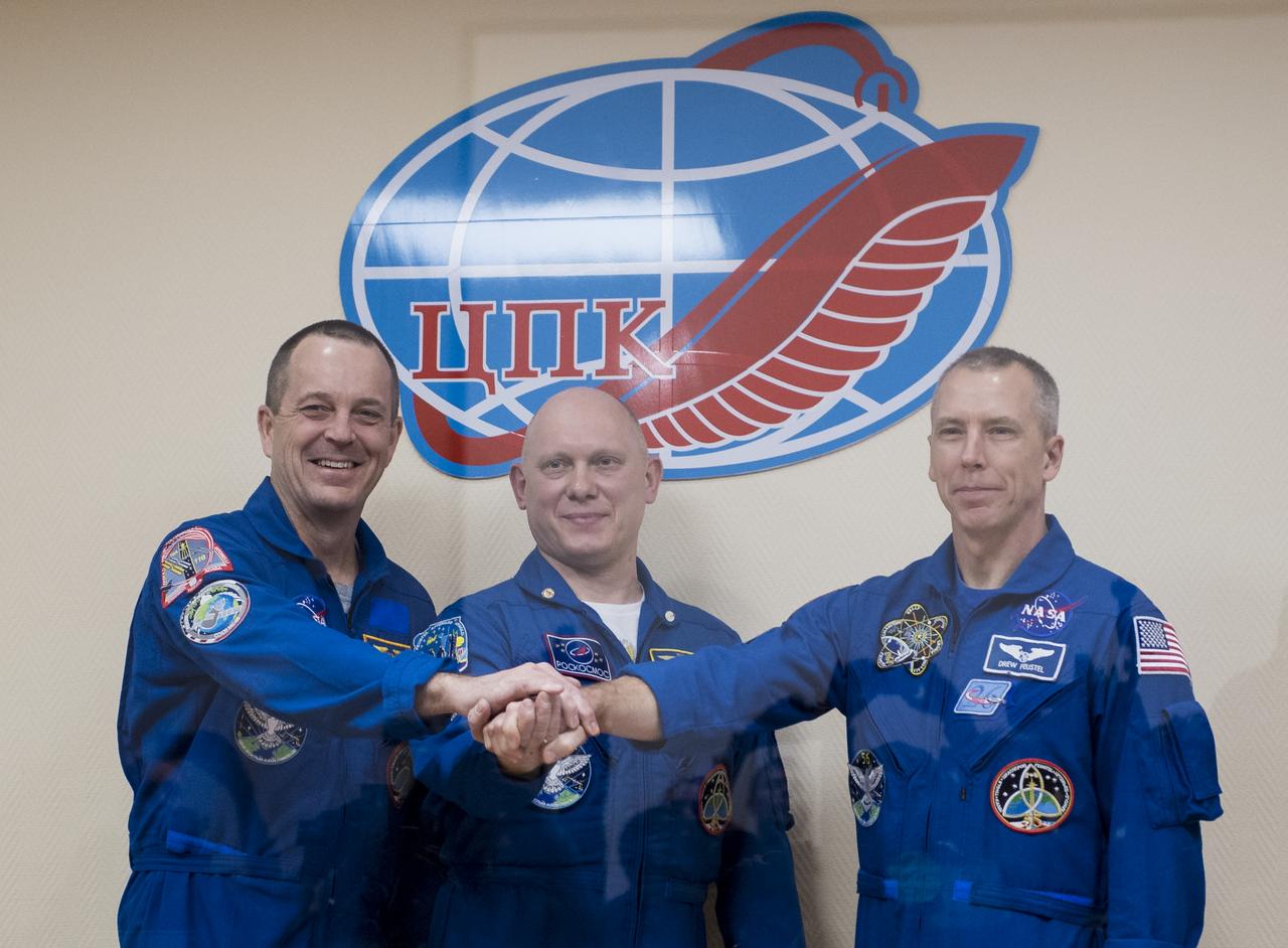 Expedition 55 flight engineer Ricky Arnold of NASA, left, Soyuz Commander Oleg Artemyev of Roscosmos, center, and flight engineer Drew Feustel of NASA, right, pose for a picture at the conclusion of a press conference, Tuesday, March 20, 2018 a the Cosmonaut Hotel in Baikonur, Kazakhstan. Arnold, Artemyev, and Feustel are scheduled to launch to the International Space Station aboard the Soyuz MS-08 spacecraft on Wednesday, March, 21.  Photo Credit: (NASA/Joel Kowsky)