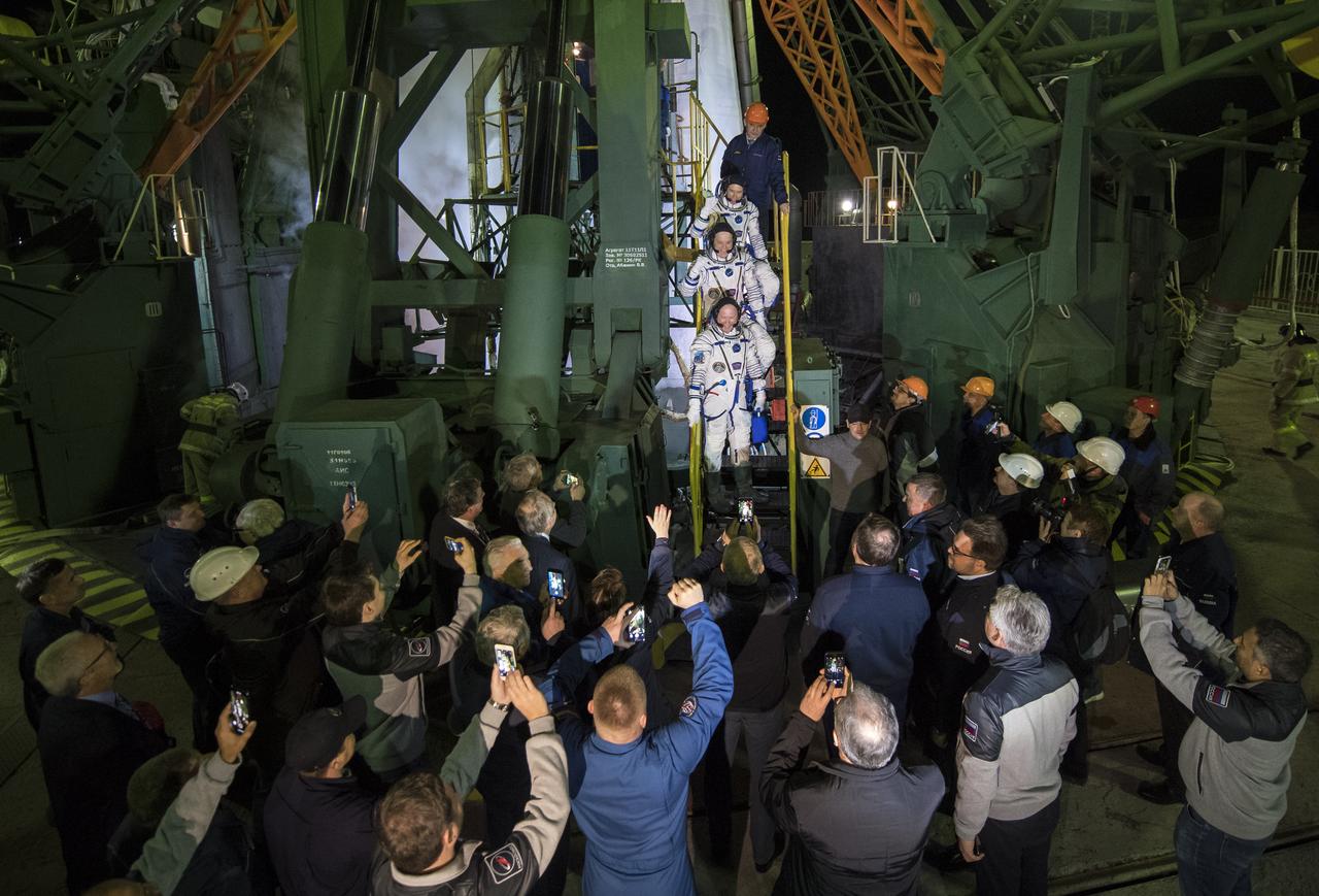 Expedition 55 flight engineer Drew Feustel of NASA, top, flight engineer Ricky Arnold of NASA, middle, and Soyuz Commander Oleg Artemyev of Roscosmos, bottom, wave farewell prior to boarding the Soyuz MS-08 spacecraft for launch, Wednesday, March 21, 2018 at the Baikonur Cosmodrome in Kazakhstan. Feustel, Arnold, and Artemyev will spend the next five months living and working aboard the International Space Station.  Photo Credit: (NASA/Joel Kowsky)