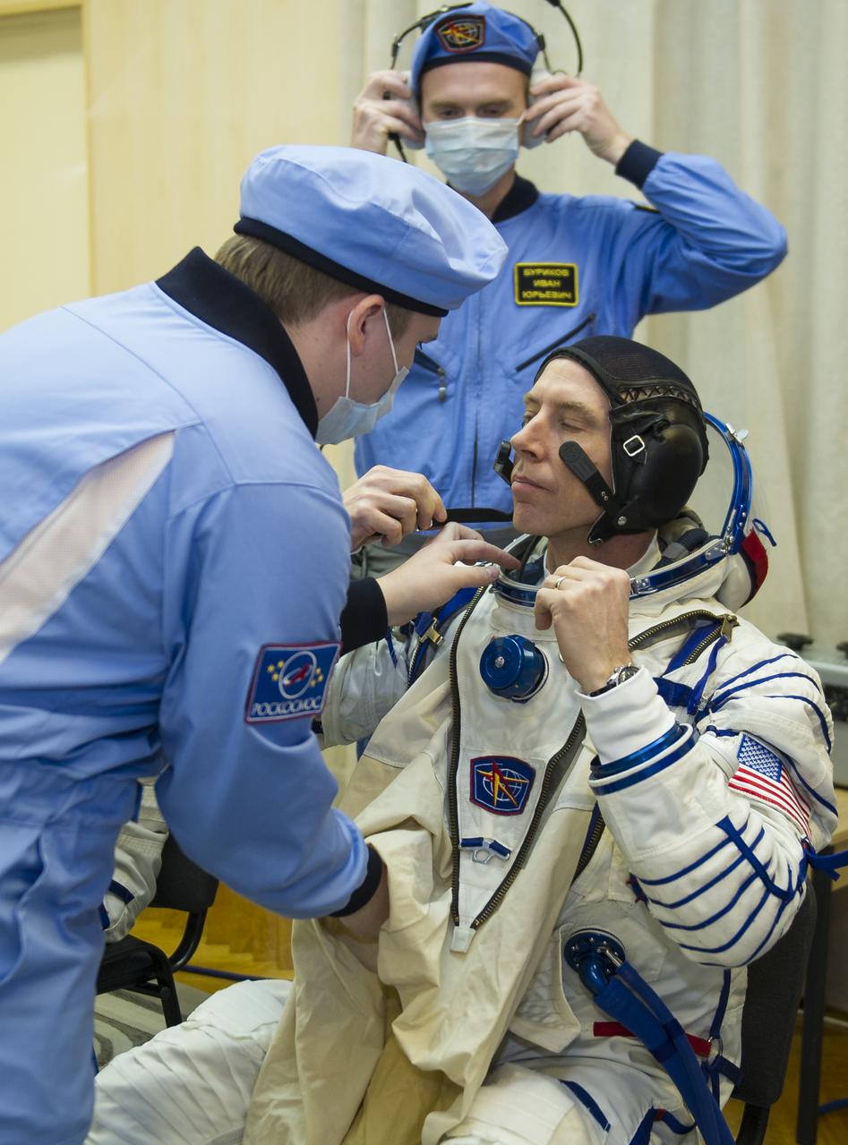 Expedition 55 flight engineer Drew Feustel of NASA is helped into his Russian Sokol suit as he and fellow crewmates, Soyuz Commander Oleg Artemyev of Roscosmos and Ricky Arnold of NASA prepare for their Soyuz launch to the International Space Station Wednesday, March 21, 2018 in Baikonur, Kazakhstan.  Feustel, Artemyev, and Arnold launched aboard the Soyuz MS-08 spacecraft at 1:44 p.m. Eastern time (11:44 p.m. Baikonur time) on March 21 to begin their journey to the International Space Station. Photo Credit: (NASA/GCTC/Irina Peshkova)