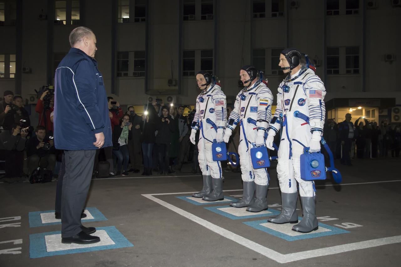 Expedition 55 flight engineer Ricky Arnold of NASA, left, Soyuz Commander Oleg Artemyev of Roscosmos, center, and flight engineer Drew Feustel of NASA, right, are seen as they depart Building 254 and report to mission managers a few hours before their launch, Wednesday, March 21, 2018 at the Baikonur Cosmodrome Kazakhstan. Launch of the Soyuz rocket will send Arnold, Artemyev, and Feustel on a five month mission aboard the International Space Station. Photo Credit: (NASA/Victor Zelentsov)
