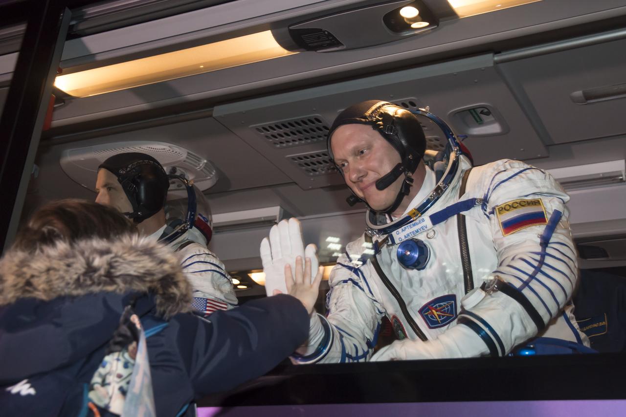 Expedition 55 Soyuz Commander Oleg Artemyev of Roscosmos waves farewell to family and friends as he and flight engineers Ricky Arnold and Drew Feustel of NASA depart for the launch pad a few hours before their launch, Wednesday, March 21, 2018 at the Baikonur Cosmodrome Kazakhstan. Launch of the Soyuz rocket will send Artemyev, Arnold, and Feustel on a five month mission aboard the International Space Station. Photo Credit: (NASA/Victor Zelentsov)