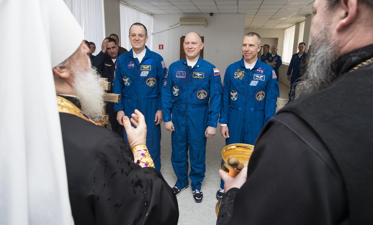 Expedition 55 flight engineer Ricky Arnold of NASA, left, Soyuz Commander Oleg Artemyev of Roscosmos, center, and flight engineer Drew Feustel, right, of NASA receive a blessing from a Russian Orthodox Priest at the Cosmonaut Hotel prior to departing the hotel for launch on a Soyuz rocket, Wednesday, March 21, 2018 in Baikonur, Kazakhstan.  Arnold, Artemyev, and Feustel will launch in their Soyuz MS-08 spacecraft to the International Space Station to begin a five month mission.  Photo Credit: (NASA/Joel Kowsky)