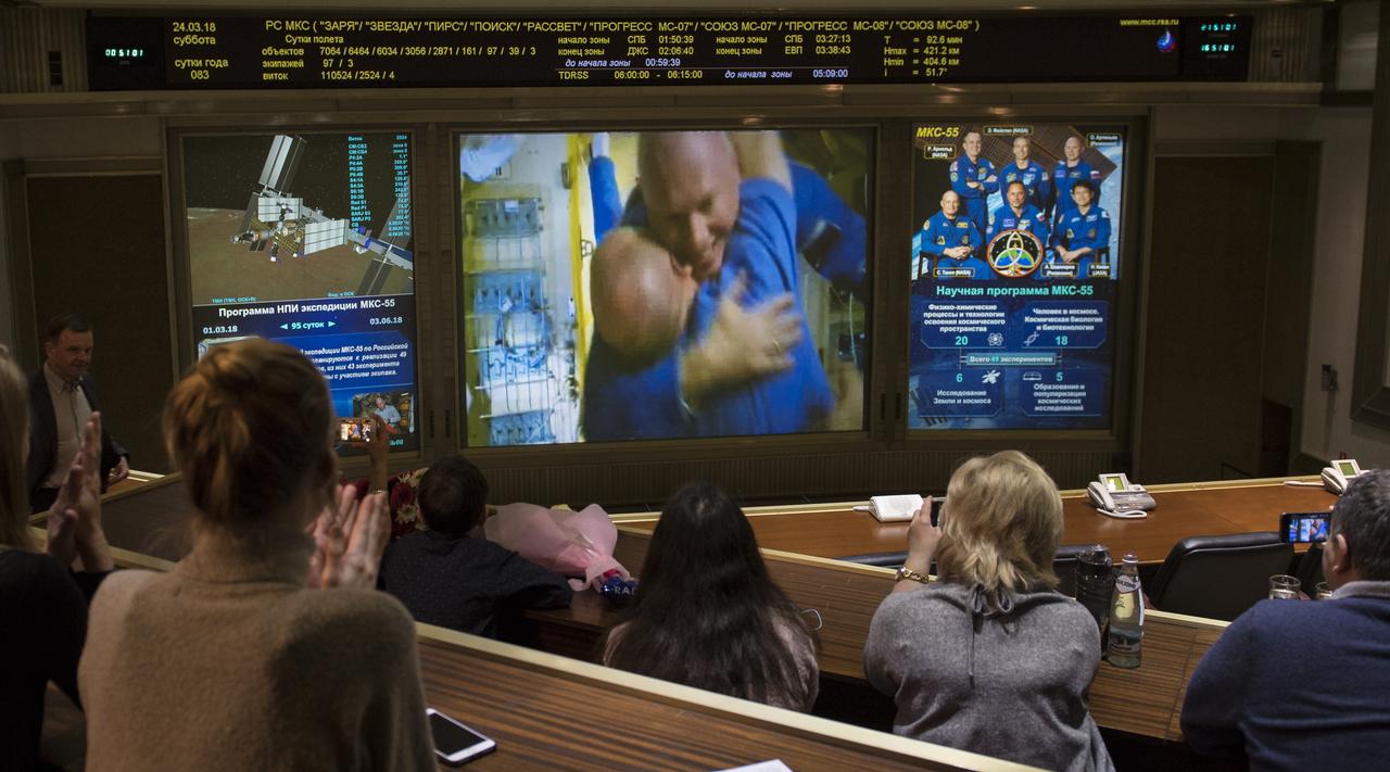 Expedition 55 flight engineer Oleg Artemyev of Roscosmos is seen embracing Scott Tingle of NASA after the hatches were opened between the Soyuz MS-08 spacecraft and the International Space Station on screens at the Moscow Mission Control Center in Korolev, Russia, Saturday, March 24, 2018, a few hours after the Soyuz MS-08 docked to the International Space Station. Hatches were opened at 5:48 p.m. Eastern time on March 23 (12:48 a.m. Moscow time on March 24) and Artemyev, Ricky Arnold of NASA and Drew Feustel of NASA joined Expedition 55 Commander Anton Shkaplerov of Roscosmos, Scott Tingle of NASA, and Norishige Kanai of the Japan Aerospace Exploration Agency (JAXA) onboard the orbiting laboratory.  Photo Credit: (NASA/Joel Kowsky)