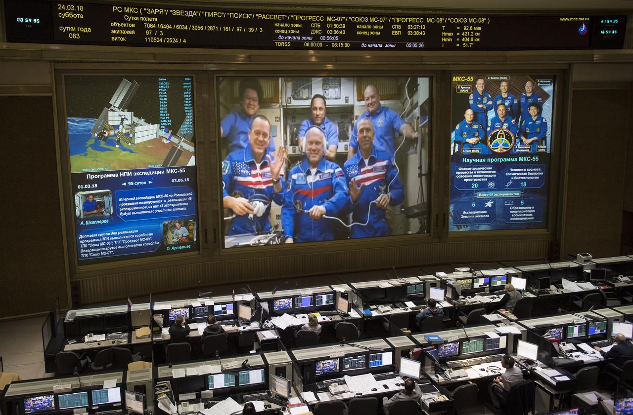 Expedition 55 flight engineers Ricky Arnold of NASA, bottom left, Oleg Artemyev of Roscosmos, bottom center, and Drew Feustel of NASA, bottom right are seen with flight engineer Norishige Kanai of the Japan Aerospace Exploration Agency (JAXA), top left, Commander Anton Shkaplerov of Roscosmos, top center, and flight engineer Scott Tingle of NASA, top right, on a video monitor as they talk to family and friends at the Moscow Mission Control Center in Korolev, Russia a few hours after the Soyuz MS-08 docked to the International Space Station on Saturday, March 24, 2018. Hatches were opened at 5:48 p.m. Eastern time on March 23, 12:48 a.m. Moscow time on March 24. Photo Credit: (NASA/Joel Kowsky)