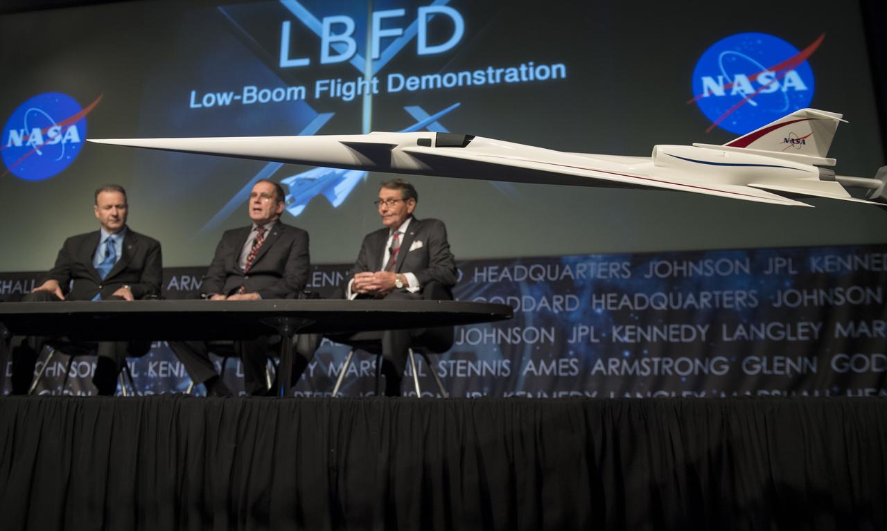 Panelists Peter Iosifidis, program manager, Low-Boom Flight Demonstrator, Lockheed Martin Skunk Works, left, Peter Coen, project manager, Commercial Supersonics Technology Project, Langley Research Center, NASA, center, and Dr. Ed Waggoner, program director, Integrated Aviation Systems Program, NASA, right, are seen behind a model of the Low Boom Flight Demonstrator at a briefing, Tuesday, April 3, 2018 at NASA Headquarters in Washington. This new experimental aircraft will cut cross country travel times in half by flying faster than the speed of sound without creating a sonic boom, enabling travel from New York to Los Angeles in two hours. Photo Credit: (NASA/Aubrey Gemignani)