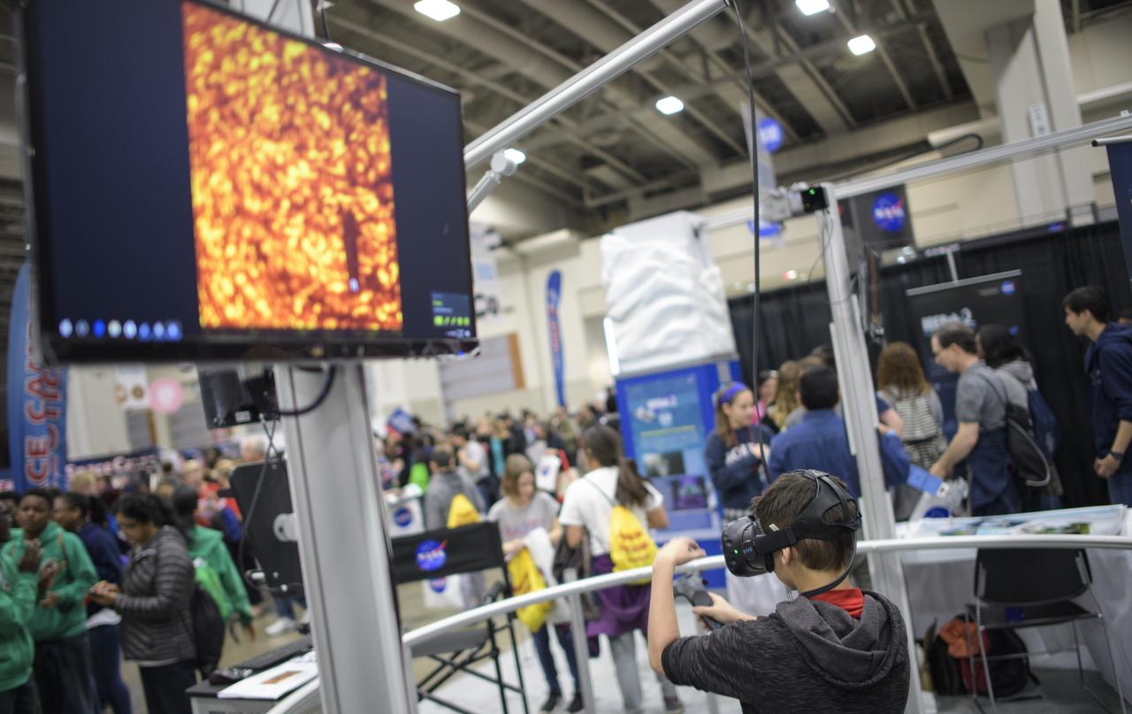An attendee uses virtual reality goggles to view the Sun during Sneak Peek Friday at the USA Science and Engineering Festival, Friday, April 6, 2018 at the Walter E. Washington Convention Center in Washington, DC.  The festival is open to the public April 7-8.  Photo Credit: (NASA/Joel Kowsky)