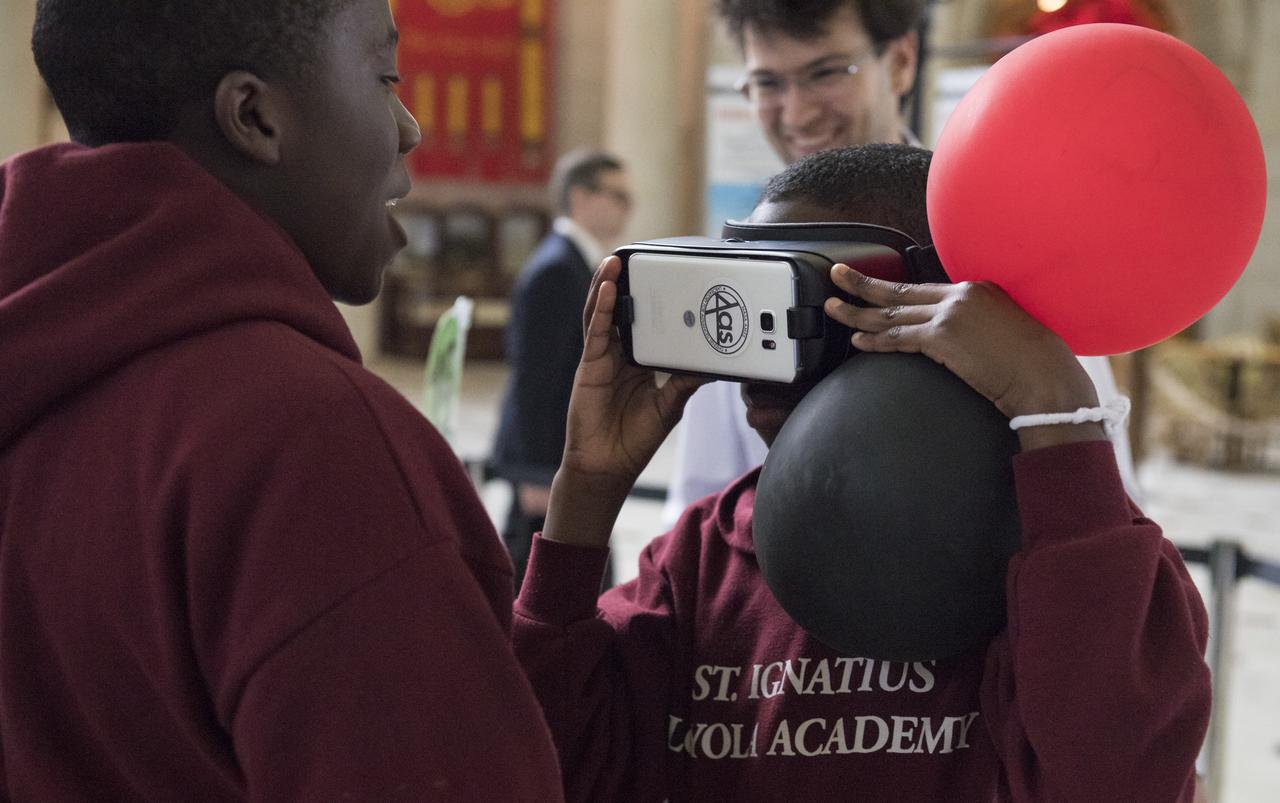 A visitor looks through virtual reality viewers at one of NASA's exhibits at the Earth Day event on Thursday, April 19, 2018 at Union Station in Washington, D.C. Photo Credit: (NASA/Aubrey Gemignani)