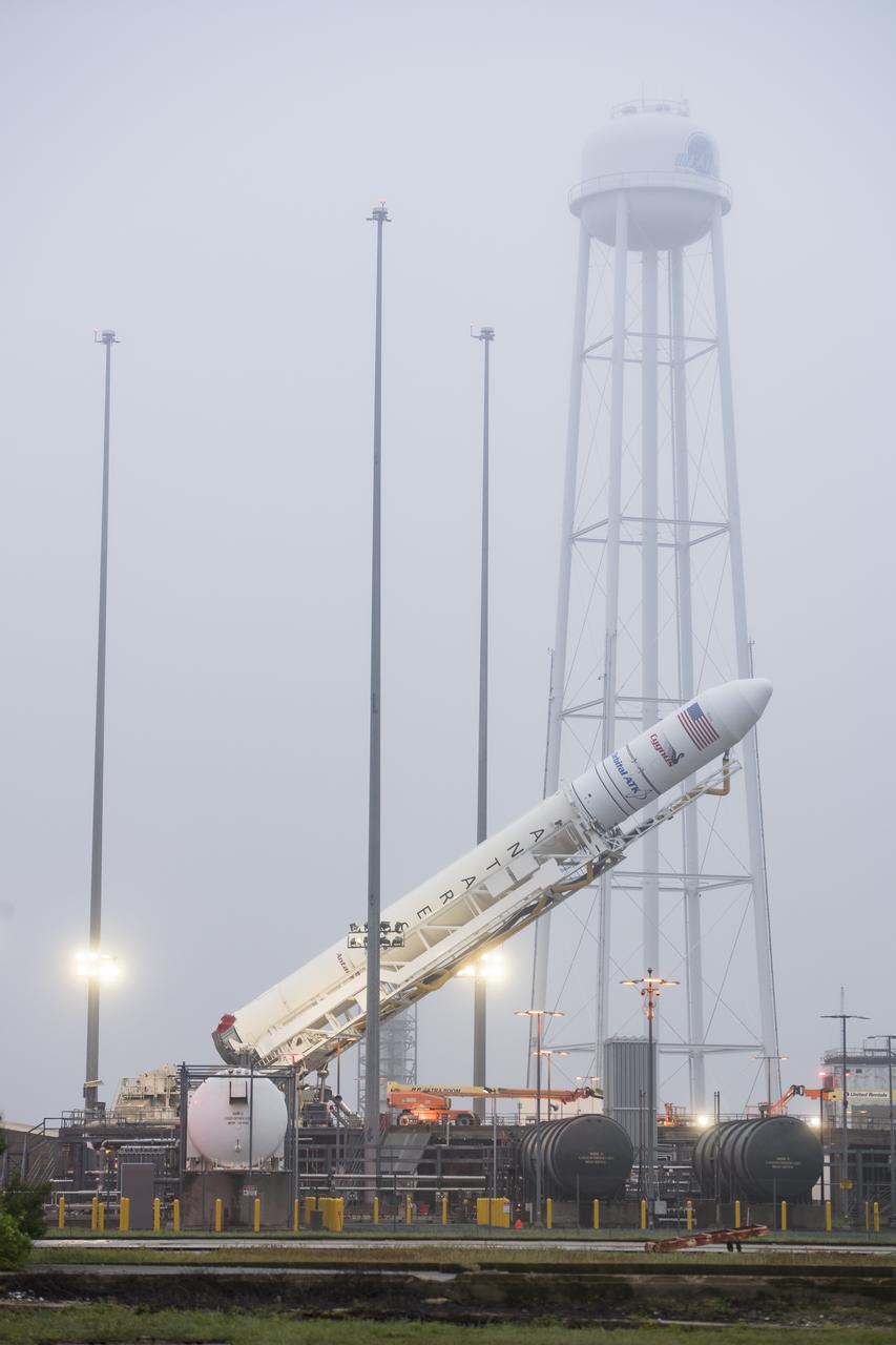 The Orbital ATK Antares rocket, with the Cygnus spacecraft onboard, is raised at launch Pad-0A, Friday, May 18, 2018 at Wallops Flight Facility in Virginia. The Antares will launch with the Cygnus spacecraft filled with 7,400 pounds of cargo for the International Space Station (ISS), including science experiments, crew supplies, and vehicle hardware. The mission is Orbital ATK's ninth contracted cargo delivery flight to ISS for NASA. Photo Credit: (NASA/Aubrey Gemignani)