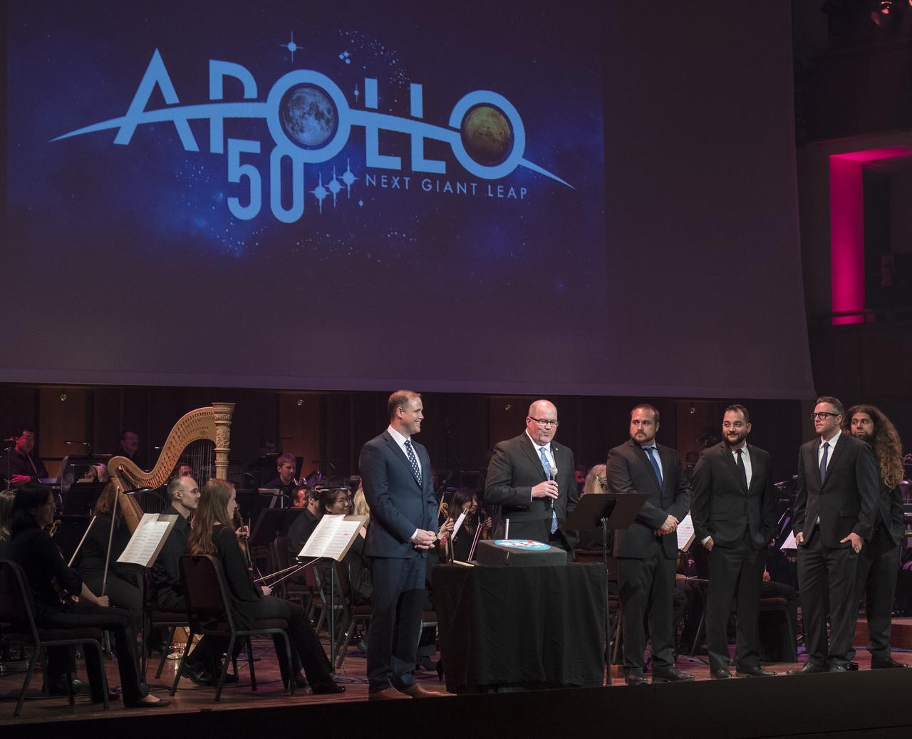 The Apollo 50th Anniversary logo is unveiled during the "National Symphony Orchestra Pops: Space, the Next Frontier" event celebrating NASA's 60th Anniversary, Friday, June 1, 2018 at the John F. Kennedy Center for the Performing Arts in Washington. The event featured music inspired by space including artists will.i.am, Grace Potter, Coheed & Cambria, John Cho, and guest Nick Sagan, son of Carl Sagan. Photo Credit: (NASA/Aubrey Gemignani)