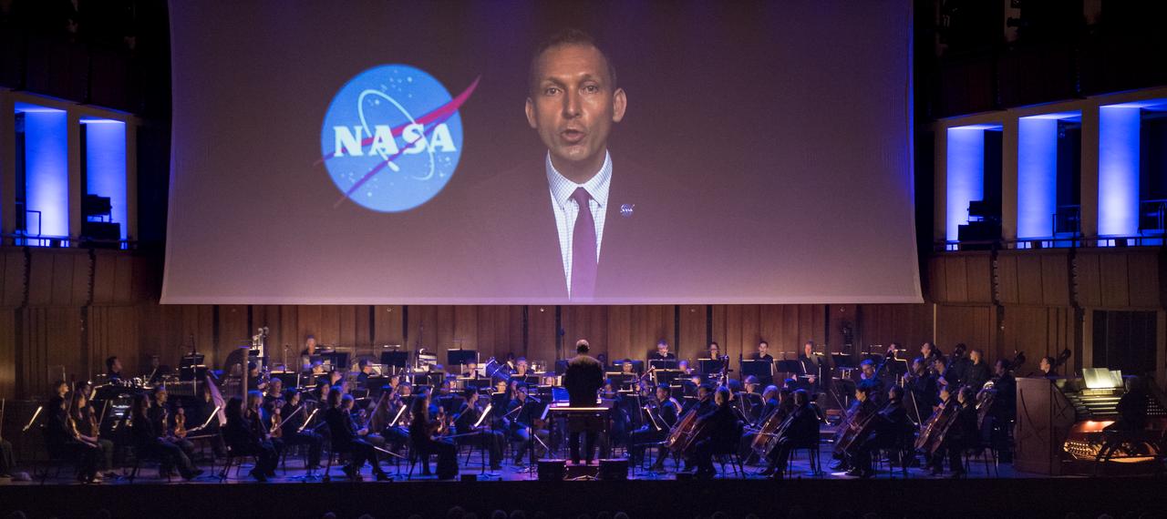 NASA's Associate Administrator for the Science Mission Directorate, Thomas Zurbuchen, is seen in a video message during the "National Symphony Orchestra Pops: Space, the Next Frontier" event celebrating NASA's 60th Anniversary, Friday, June 1, 2018 at the John F. Kennedy Center for the Performing Arts in Washington. The event featured music inspired by space including artists will.i.am, Grace Potter, Coheed & Cambria, John Cho, and guest Nick Sagan, son of Carl Sagan. Photo Credit: (NASA/Aubrey Gemignani)