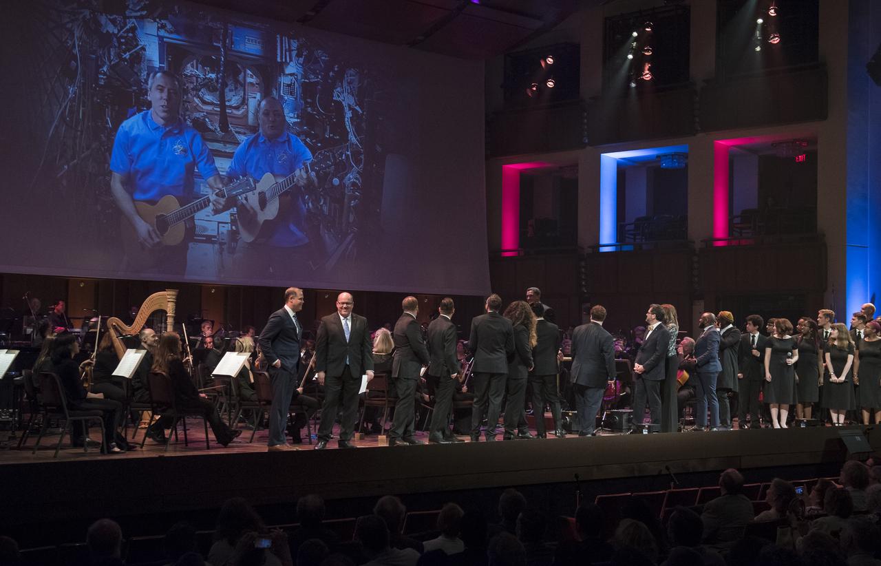 NASA astronauts Drew Feustel, left, and Scott Tingle, perform a song by video at the "National Symphony Orchestra Pops: Space, the Next Frontier" event celebrating NASA's 60th Anniversary, Friday, June 1, 2018 at the John F. Kennedy Center for the Performing Arts in Washington. The event featured music inspired by space including artists will.i.am, Grace Potter, Coheed & Cambria, John Cho, and guest Nick Sagan, son of Carl Sagan. Photo Credit: (NASA/Aubrey Gemignani)