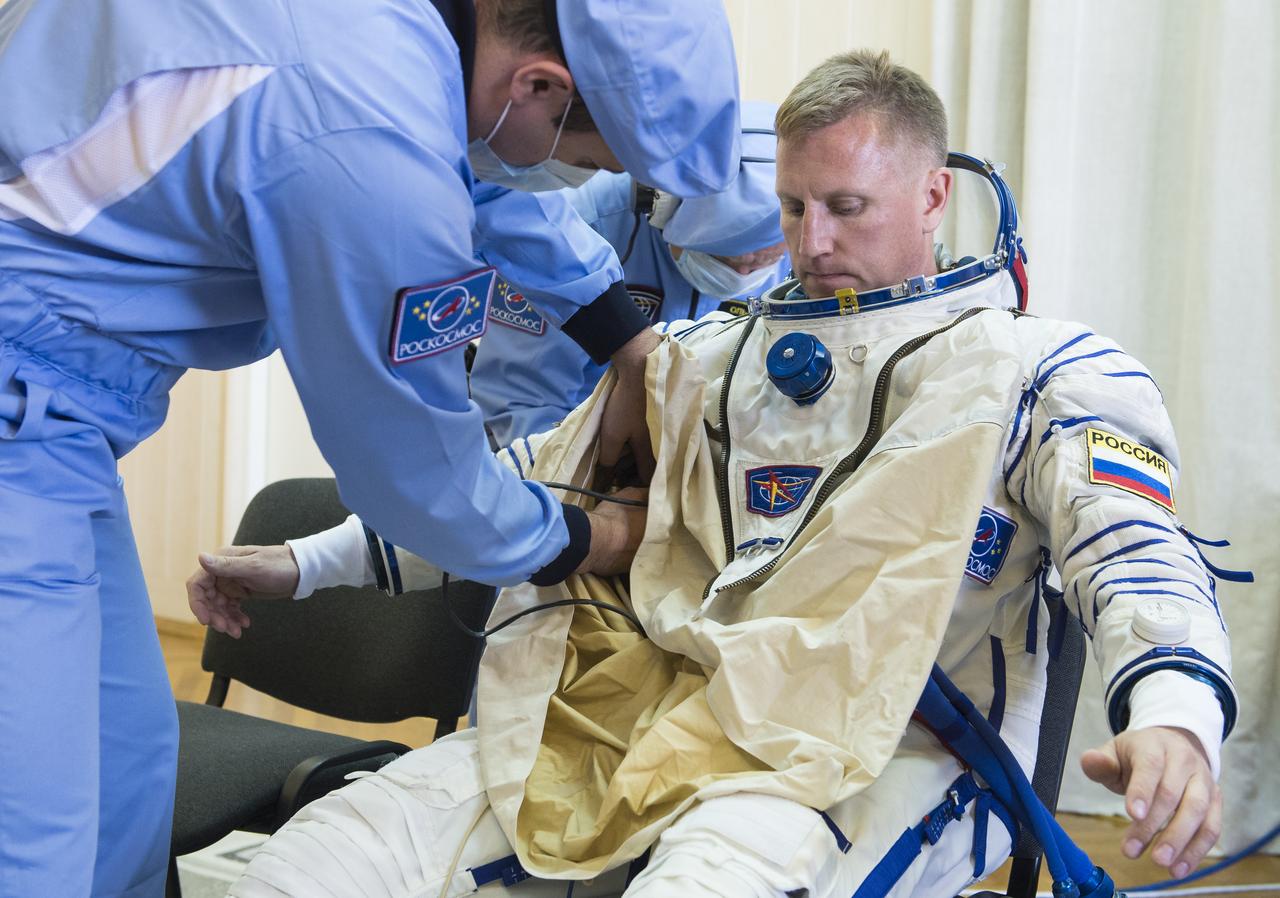 Expedition 56 Soyuz Commander Sergey Prokopyev of Roscosmos is helped into his Russian Sokol suit as he and fellow crewmates, Serena Auñón-Chancellor of NASA and Alexander Gerst of ESA (European Space Agency) prepare for their Soyuz launch to the International Space Station, Wednesday, June 6, 2018 at the Baikonur Cosmodrome in Kazakhstan.  Launch of the Soyuz rocket will send Prokopyev, Auñón-Chancellor, and Gerst on a six month mission aboard the International Space Station. Photo Credit: (NASA/GCTC/Andrey Shelepin)