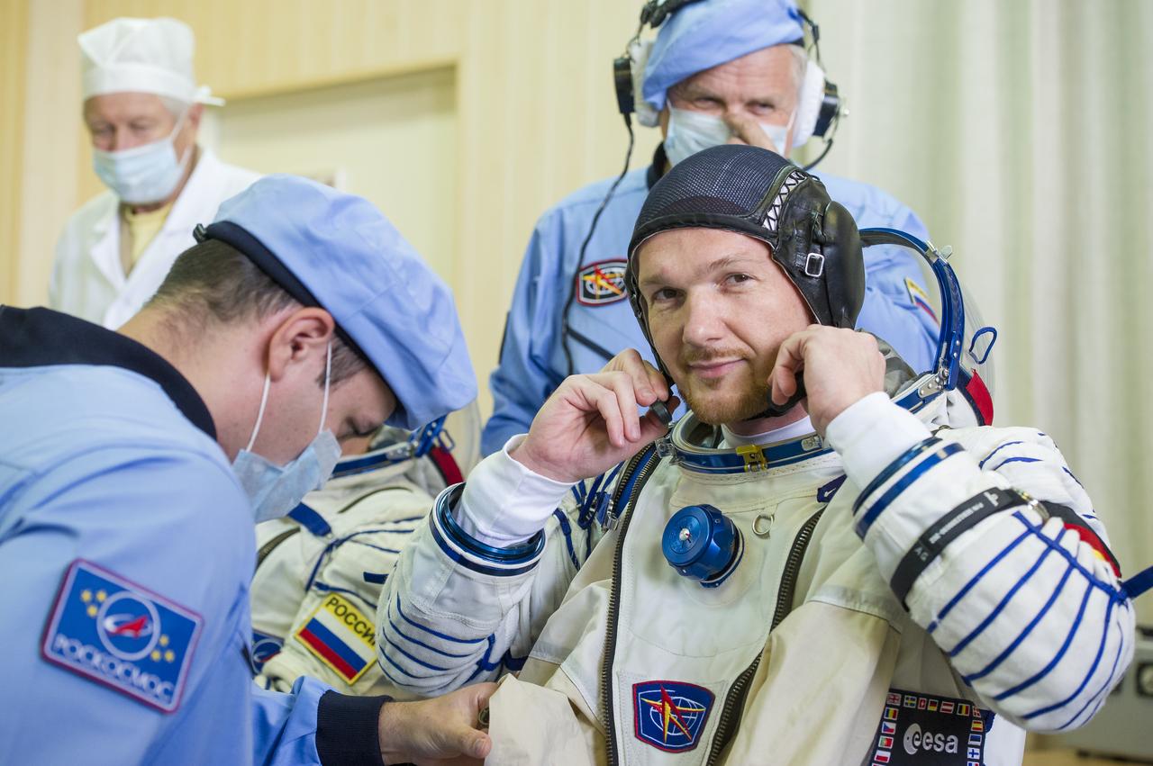 Expedition 56 flight engineer Alexander Gerst of ESA (European Space Agency) is helped into his Russian Sokol suit as he and fellow crewmates, Serena Auñón-Chancellor of NASA and Sergey Prokopyev of Roscosmos prepare for their Soyuz launch to the International Space Station, Wednesday, June 6, 2018 at the Baikonur Cosmodrome in Kazakhstan.  Launch of the Soyuz rocket will send Gerst, Auñón-Chancellor, and Prokopyev on a six month mission aboard the International Space Station. Photo Credit: (NASA/GCTC/Andrey Shelepin)