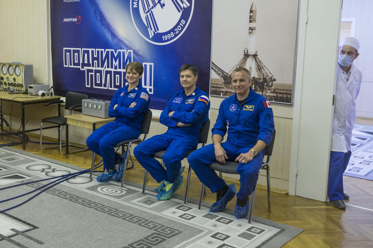 Expedition 56 backup crew members Anne McClain of NASA, left, Oleg Kononenko of Roscosmos, center, and David Saint-Jacques of the Canadian Space Agency, right, are seen as they watch prime crew members Serena Auñón-Chancellor of NASA, Sergey Prokopyev of Roscosmos, and Alexander Gerst of ESA (European Space Agency) talk with family and friends after having their Russian Sokol suits pressure checked in preparation for launch aboard the Soyuz MS-09 spacecraft, Wednesday, June 6, 2018 at the Baikonur Cosmodrome in Kazakhstan. Auñón-Chancellor, Prokopyev, and Gerst launched aboard the Soyuz MS-09 spacecraft at 7:12am EDT (5:12pm Baikonur time) on June 6 to begin their journey to the International Space Station. Photo Credit: (NASA/Victor Zelentsov)