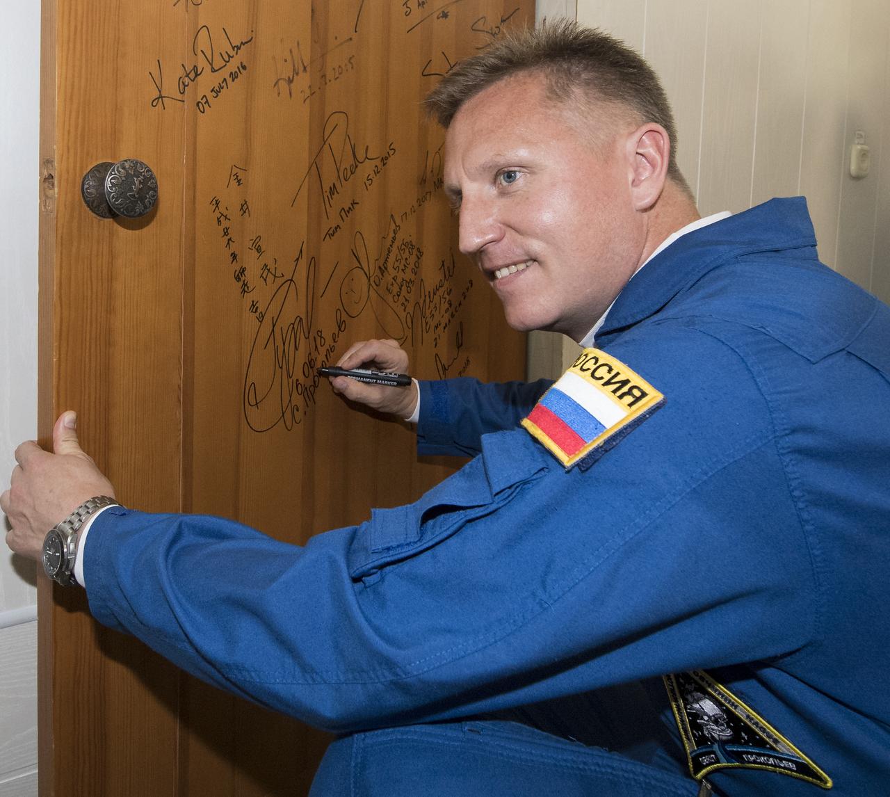 Expedition 56 Soyuz Commander Sergey Prokopyev of Roscosmos performs the traditional door signing at the Cosmonaut Hotel prior to departing the hotel for launch on a Soyuz rocket with fellow crewmates Serena Auñón-Chancellor of NASA and Alexander Gerst of ESA (European Space Agency), Wednesday, June 6, 2018 in Baikonur, Kazakhstan.  Prokopyev, Auñón-Chancellor, and Gerst will launch in their Soyuz MS-09 spacecraft to the International Space Station to being a six month mission.  Photo Credit: (NASA/Joel Kowsky)