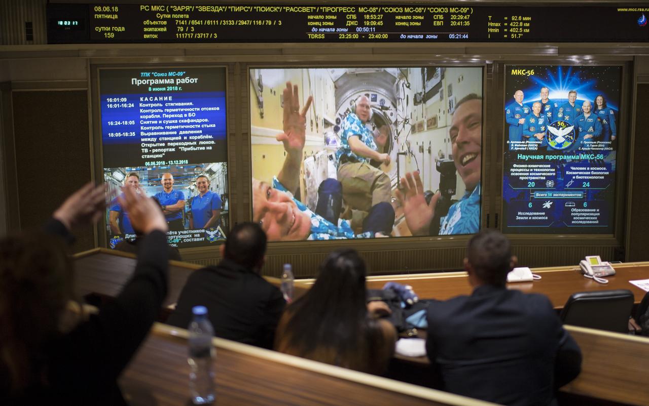 Expedition 56 flight engineers Ricky Arnold of NASA, left, Oleg Artemyev of Roscosmos, center, and Commander Drew Feustel are seen waving as they wait for the Soyuz hatch to open on a screen in the Moscow Mission Control Center in Korolev, Russia a few hours after the Soyuz MS-09 docked to the International Space Station on Friday, June 8, 2018. Hatches were opened at 11:17am EDT (6:17pm Moscow time) and Serena Auñón-Chancellor of NASA, Sergey Prokopyev of Roscosmos, and Alexander Gerst of ESA (European Space Agency) joined Expedition 56 Commander Drew Feustel of NASA, Ricky Arnold of NASA, and Oleg Artemyev of Roscosmos onboard the orbiting laboratory.  Photo Credit: (NASA/Joel Kowsky)