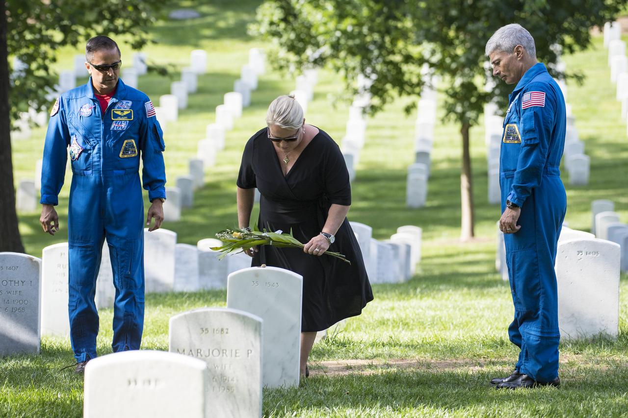 NASA astronaut Joe Acaba, left, and Mark Vande Hei, right, watch as Julie Vande Hei, wife of Mark, places a flower at the gravesite of former astronaut and U.S. Senator John Glenn, Friday, June 15, 2018 at the Arlington National Cemetery in Arlington, Va. Photo Credit: (NASA/Aubrey Gemignani)