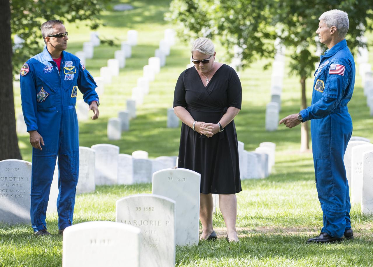 NASA astronaut Joe Acaba, left, and Mark Vande Hei, right, watch as Julie Vande Hei, wife of Mark, takes a moment after placing a flower at the gravesite of former astronaut and U.S. Senator John Glenn, Friday, June 15, 2018 at the Arlington National Cemetery in Arlington, Va. Photo Credit: (NASA/Aubrey Gemignani)