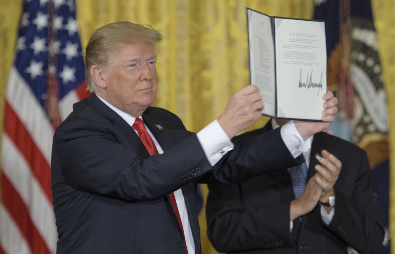 President Donald Trump holds up Space Policy Directive - 3 after signing it during a meeting of the National Space Council in the East Room of the White House, Monday, June 18, 2018, in Washington. Chaired by the Vice President, the council's role is to advise the President regarding national space policy and strategy, and review the nation's long-range goals for space activities. Photo Credit: (NASA/Bill Ingalls)