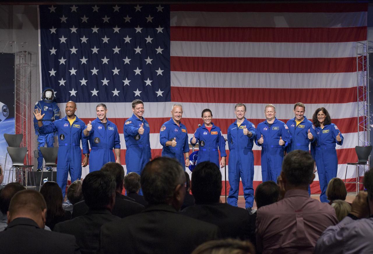 The first U.S. astronauts who will fly on American-made, commercial spacecraft to and from the International Space Station, wave after being announced, Friday, Aug. 3, 2018 at NASA's Johnson Space Center in Houston, Texas. The astronauts are, from left to right: Victor Glover, Mike Hopkins, Bob Behnken, Doug Hurley, Nicole Aunapu Mann, Chris Ferguson, Eric Boe, Josh Cassada, and Suni Williams. The agency assigned the nine astronauts to crew the first flight tests and missions of the Boeing CST-100 Starliner and SpaceX Crew Dragon. Photo Credit: (NASA/Bill Ingalls)
