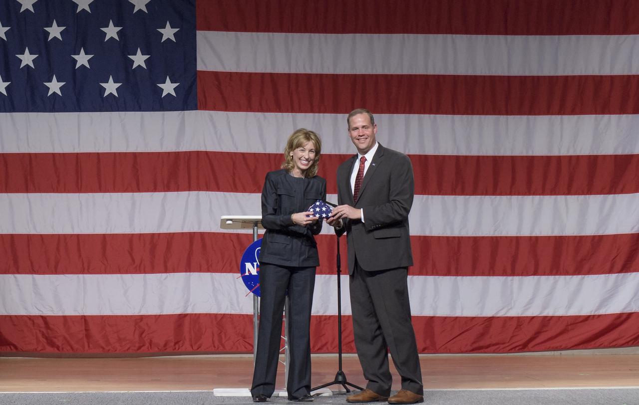 Boeing Defense, Space and Security President and CEO Leanne Caret receives an American flag from NASA Administrator Jim Bridenstine during a NASA event announcing the astronauts assigned to crew the first flight tests and missions of the Boeing CST-100 Starliner and SpaceX Crew Dragon, Friday, Aug. 3, 2018 at NASA’s Johnson Space Center in Houston, Texas. The flag is to be flown to the International Space Station onboard the test flight of Starliner and retrieved later during the first mission of the Starliner.  Photo Credit: (NASA/Bill Ingalls)