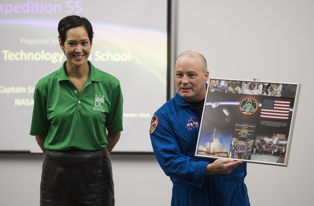 NASA astronaut Scott Tingle presents a montage for Washington, DC's Office of the Deputy Mayor for Education to Ahnna Smith, Interim Deputy Mayor for Education, prior to speaking to students about his time onboard the International Space Station, Friday, Sept. 14, 2018 at McKinley Technology High School in Washington, DC. Tingle spent 168 days onboard the International Space Station as part of Expeditions 54 and 55. Photo Credit: (NASA/Joel Kowsky)