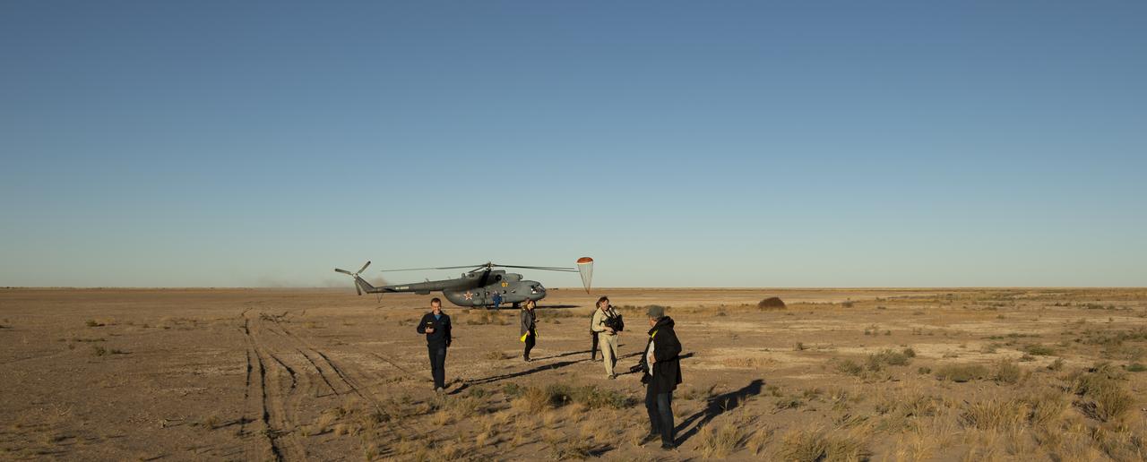 A pilot parachute for the Soyuz MS-08 spacecraft lands behind a support helicopter at the landing site of Expedition 56 Commander Drew Feustel and Flight Engineer Ricky Arnold of NASA, along with Flight Engineer and Soyuz Commander Oleg Artemyev of Roscosmos near the town of Zhezkazgan, Kazakhstan on Thursday, Oct. 4, 2018. Feustel, Arnold, and Artemyev are returning after 197 days in space where they served as members of the Expedition 55 and 56 crews onboard the International Space Station. Photo Credit: (NASA/Bill Ingalls)