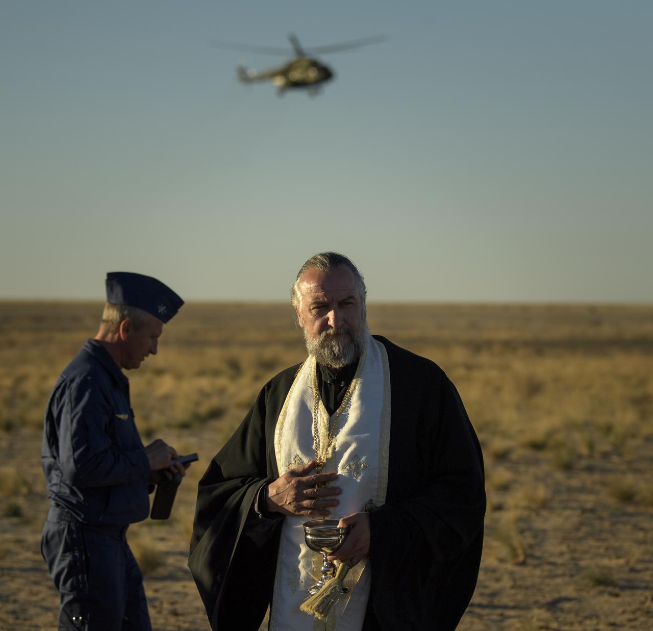 Russian Orthodox Priest, Father Alexander, watches over the landing zone after the Soyuz MS-08 spacecraft landed with Expedition 56 Commander Drew Feustel and Flight Engineer Ricky Arnold of NASA, along with Flight Engineer and Soyuz Commander Oleg Artemyev of Roscosmos near the town of Zhezkazgan, Kazakhstan on Thursday, Oct. 4, 2018. Feustel, Arnold, and Artemyev are returning after 197 days in space where they served as members of the Expedition 55 and 56 crews onboard the International Space Station. Photo Credit: (NASA/Bill Ingalls)