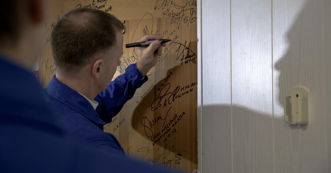 Expedition 57 Flight Engineer Nick Hague of NASA signs a door in the Cosmonaut Hotel prior to departing for launch on a Soyuz rocket with Flight Engineer Alexey Ovchinin of Roscosmos, Thursday, Oct. 11, 2018 in Baikonur, Kazakhstan. During the Soyuz spacecraft's climb to orbit, an anomaly occurred, resulting in an abort downrange. The crew was quickly recovered and is in good condition. Photo Credit: (NASA/Bill Ingalls)