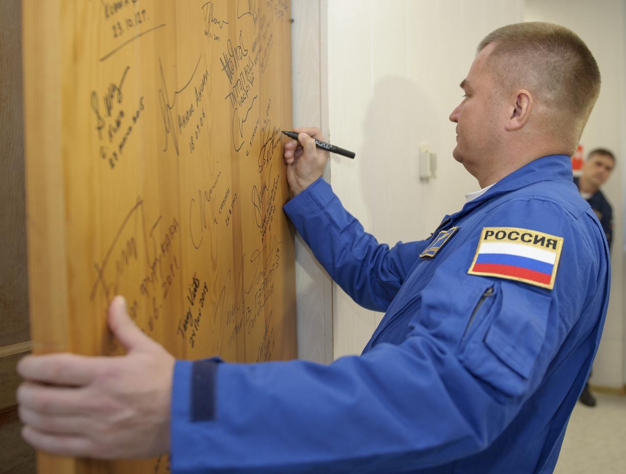 Expedition 57 Flight Engineer Alexey Ovchinin of Roscosmos signs a door in the Cosmonaut Hotel prior to departing for launch on a Soyuz rocket with Flight Engineer Nick Hague of NASA, Thursday, Oct. 11, 2018 in Baikonur, Kazakhstan.  During the Soyuz spacecraft's climb to orbit, an anomaly occurred, resulting in an abort downrange. The crew was quickly recovered and is in good condition. Photo Credit: (NASA/GCTC/Irina Spector)