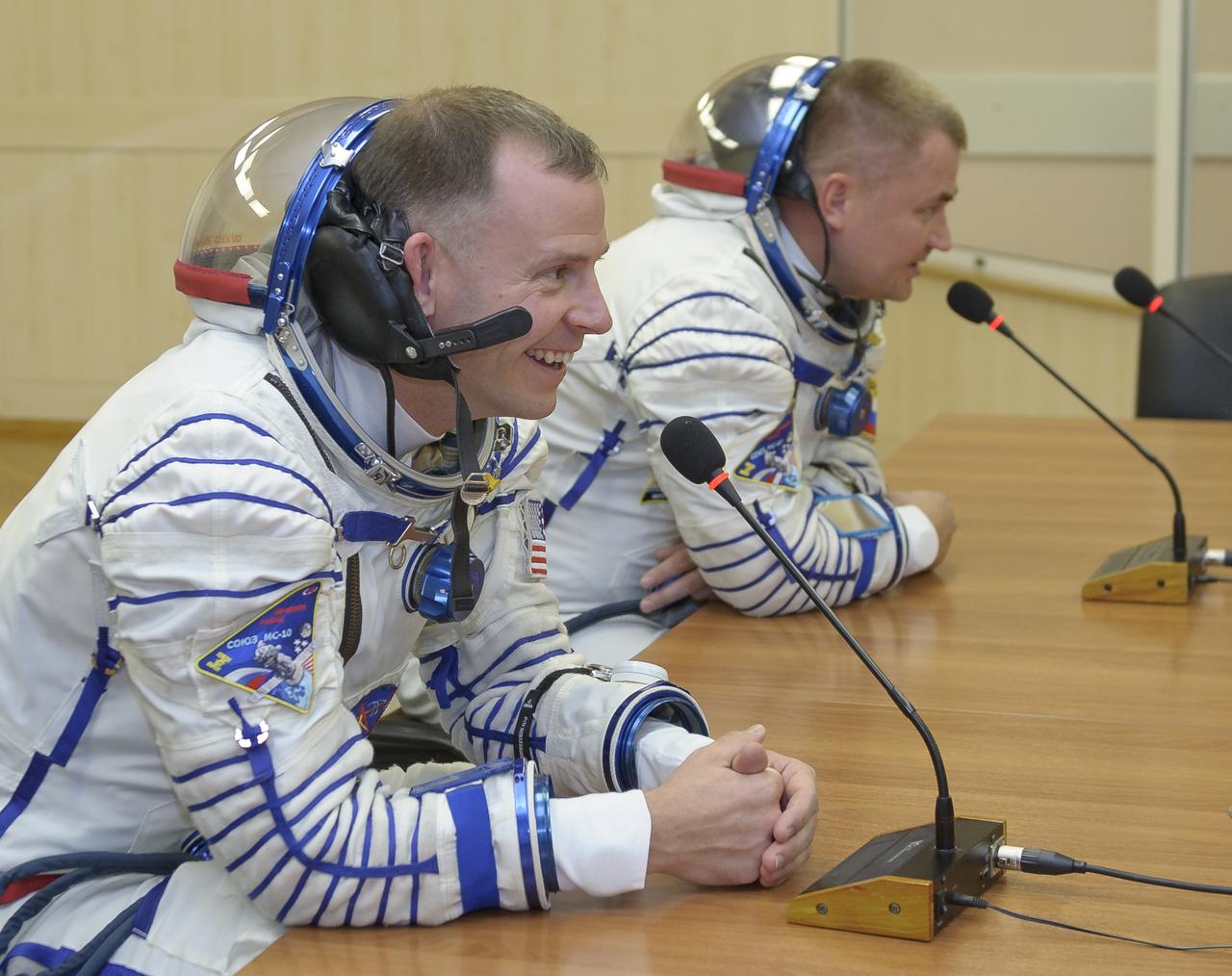 Expedition 57 Flight Engineer Nick Hague of NASA, left, and Flight Engineer Alexey Ovchinin of Roscosmos talk to family members after having donned their Sokol suits for their launch on a Soyuz rocket, Thursday, Oct. 11, 2018 at the Baikonur Cosmodrome in Kazakhstan. During the Soyuz spacecraft's climb to orbit, an anomaly occurred, resulting in an abort downrange. The crew was quickly recovered and is in good condition. Photo Credit: (NASA/GCTC/Irina Spector)