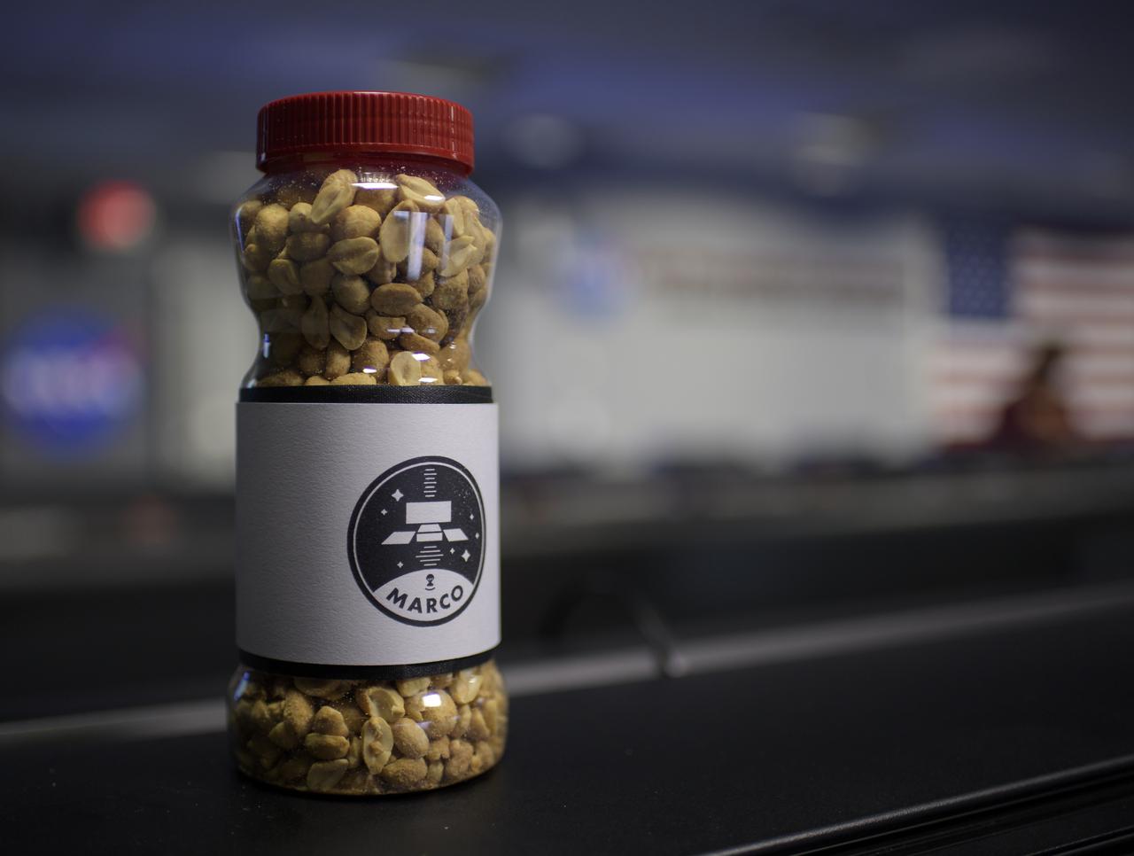 A jar of nuts with the Mars Cube One (MarCO) logo is seen inside the Mission Control Area (MSA) where teams are starting to gather for the Mars InSight landing, Monday, Nov. 26, 2018 inside the Mission Support Area at NASA's Jet Propulsion Laboratory in Pasadena, California. Good-luck peanuts made their first appearance at the Jet Propulsion Laboratory's Space Flight Operations Facility in 1964 during the Ranger 7 mission. InSight, short for Interior Exploration using Seismic Investigations, Geodesy and Heat Transport, is a Mars lander designed to study the "inner space" of Mars: its crust, mantle, and core. Photo Credit: (NASA/Bill Ingalls)