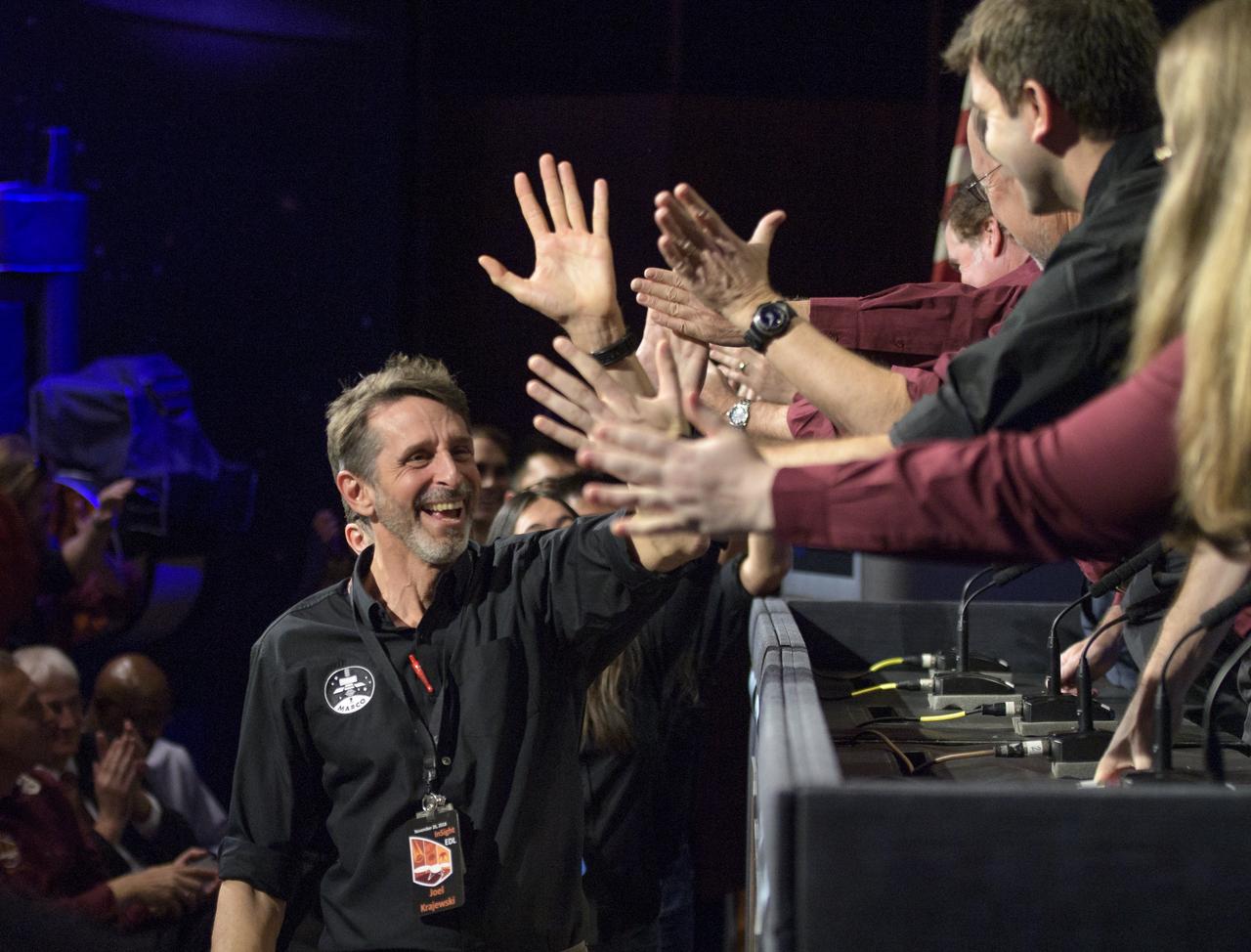 Mars Cube One and Mars InSight team members give each other high fives at the conclusion of a Mars InSight post-landing  press conference, Monday, Nov. 26, 2018 at NASA's Jet Propulsion Laboratory in Pasadena, California. InSight, short for Interior Exploration using Seismic Investigations, Geodesy and Heat Transport, is a Mars lander designed to study the "inner space" of Mars: its crust, mantle, and core. Photo Credit: (NASA/Bill Ingalls)