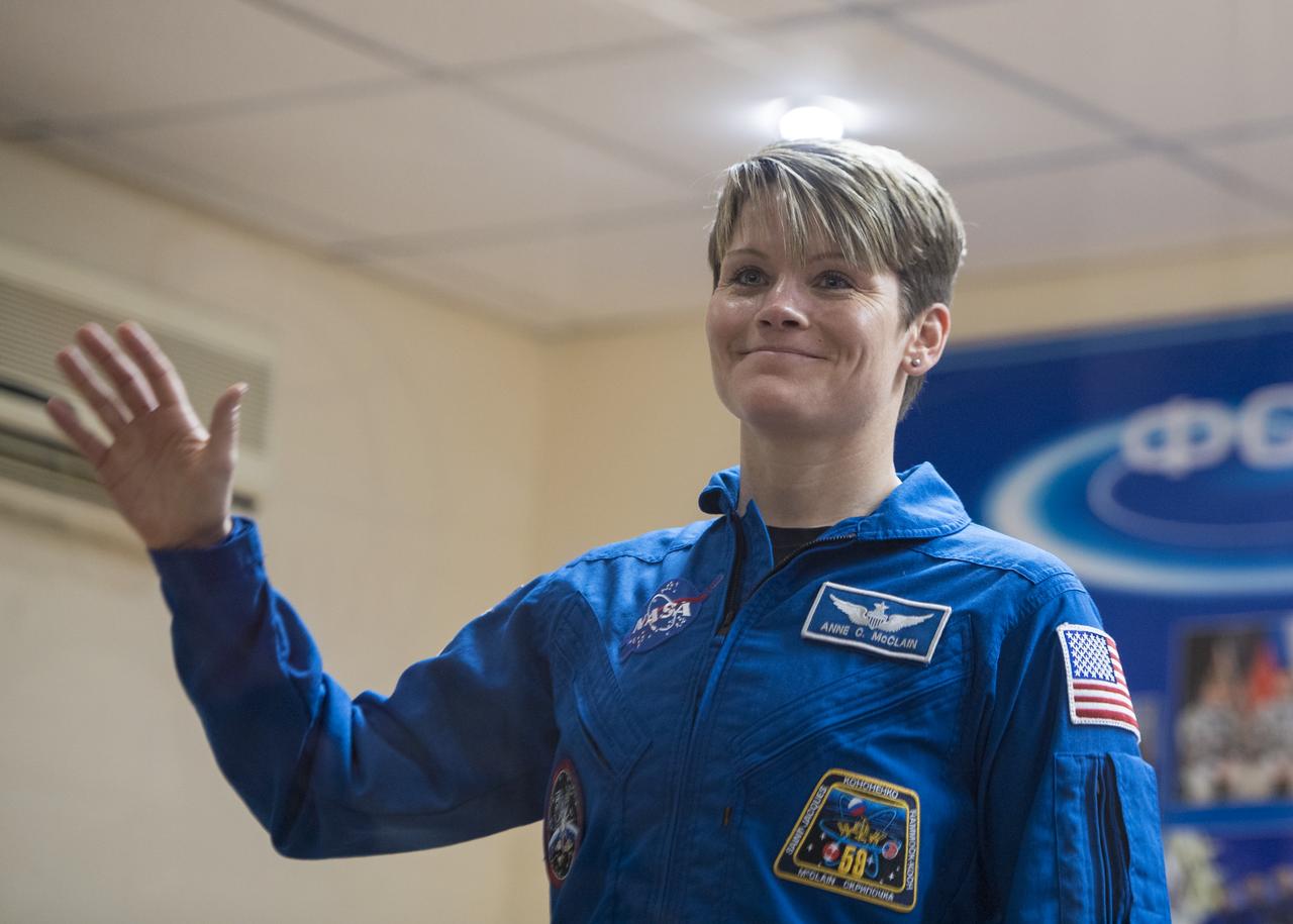 Expedition 58 Flight Engineer Anne McClain of NASA waves during a press conference, Sunday, Dec. 2, 2018 at the Cosmonaut Hotel in Baikonur, Kazakhstan. Launch of the Soyuz rocket is scheduled for Dec. 3 and will carry McClain, Soyuz Commander Oleg Kononenko of Roscosmos, and David Saint-Jacques of the Canadian Space Agency (CSA) into orbit to begin their six and a half month mission on the International Space Station. Photo Credit: (NASA/Aubrey Gemignani).